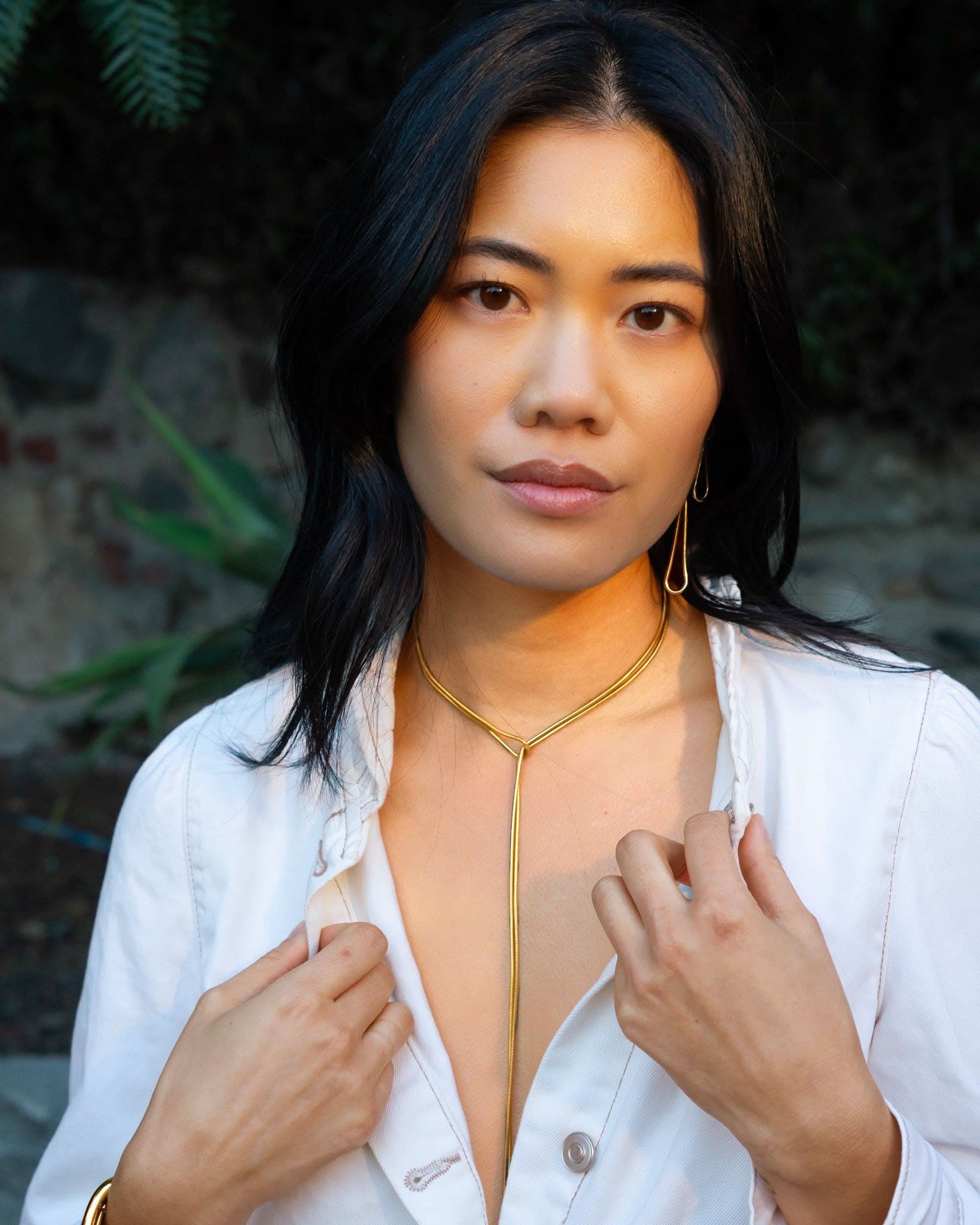 Woman wearing a white jacket with a gold trim, standing outdoors.