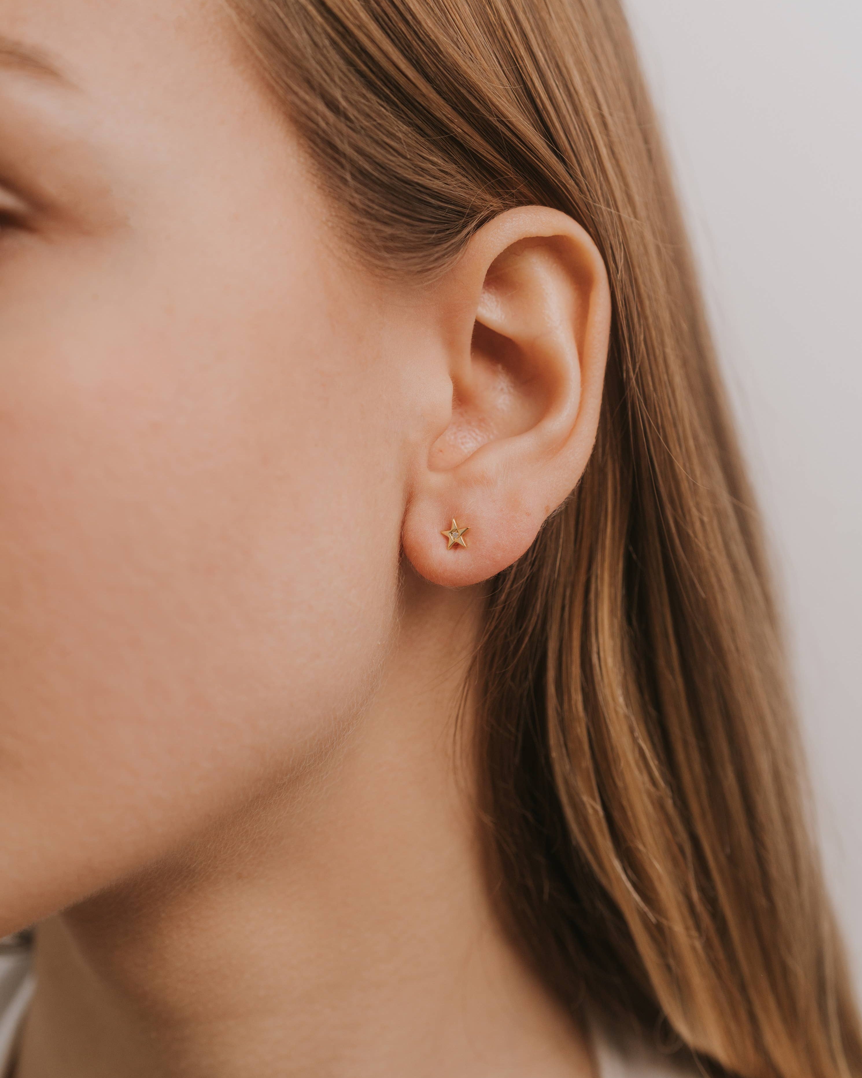 Close-up of a person wearing a star gold earring