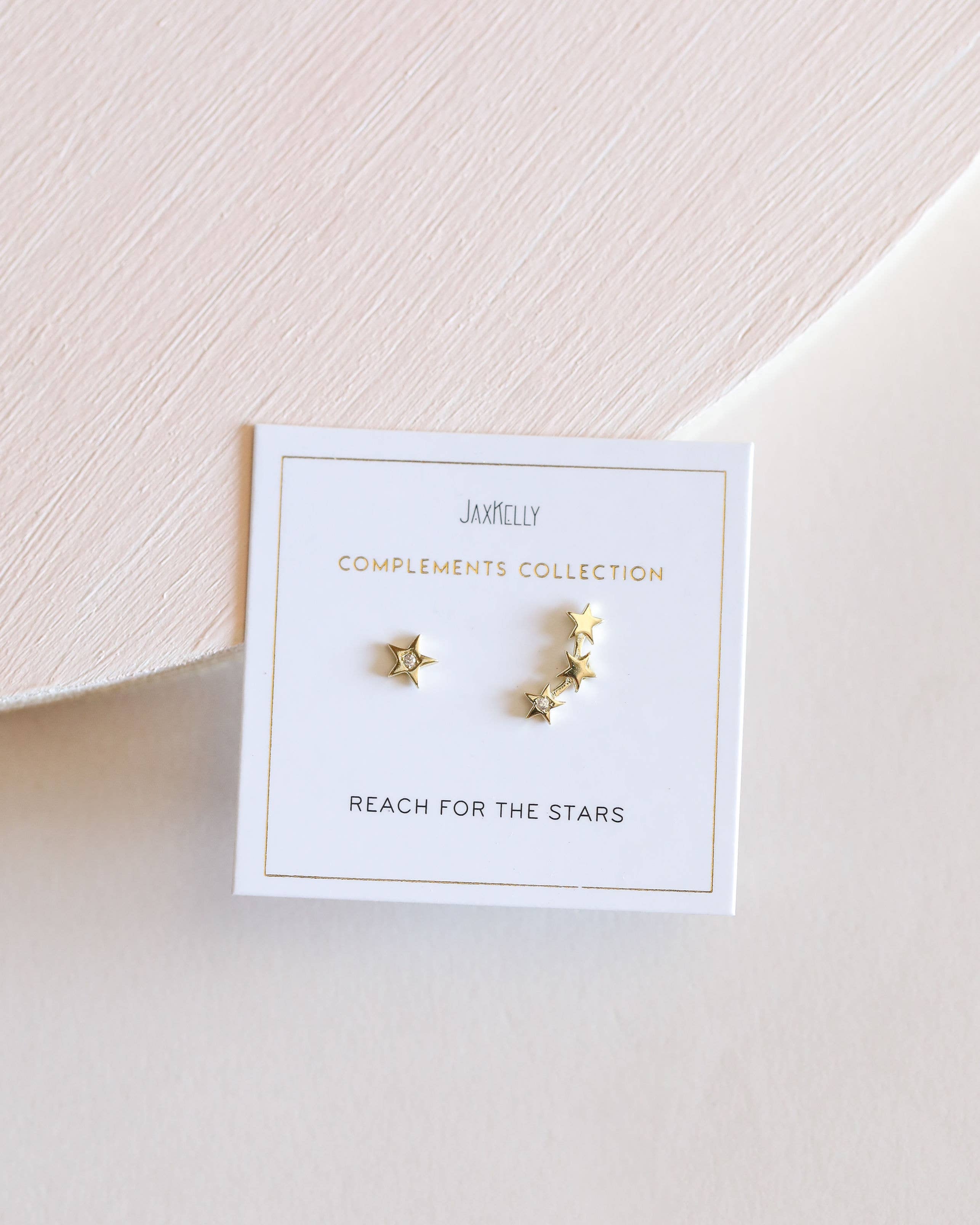 Gold star-shaped earrings on a Jamelly branded card
