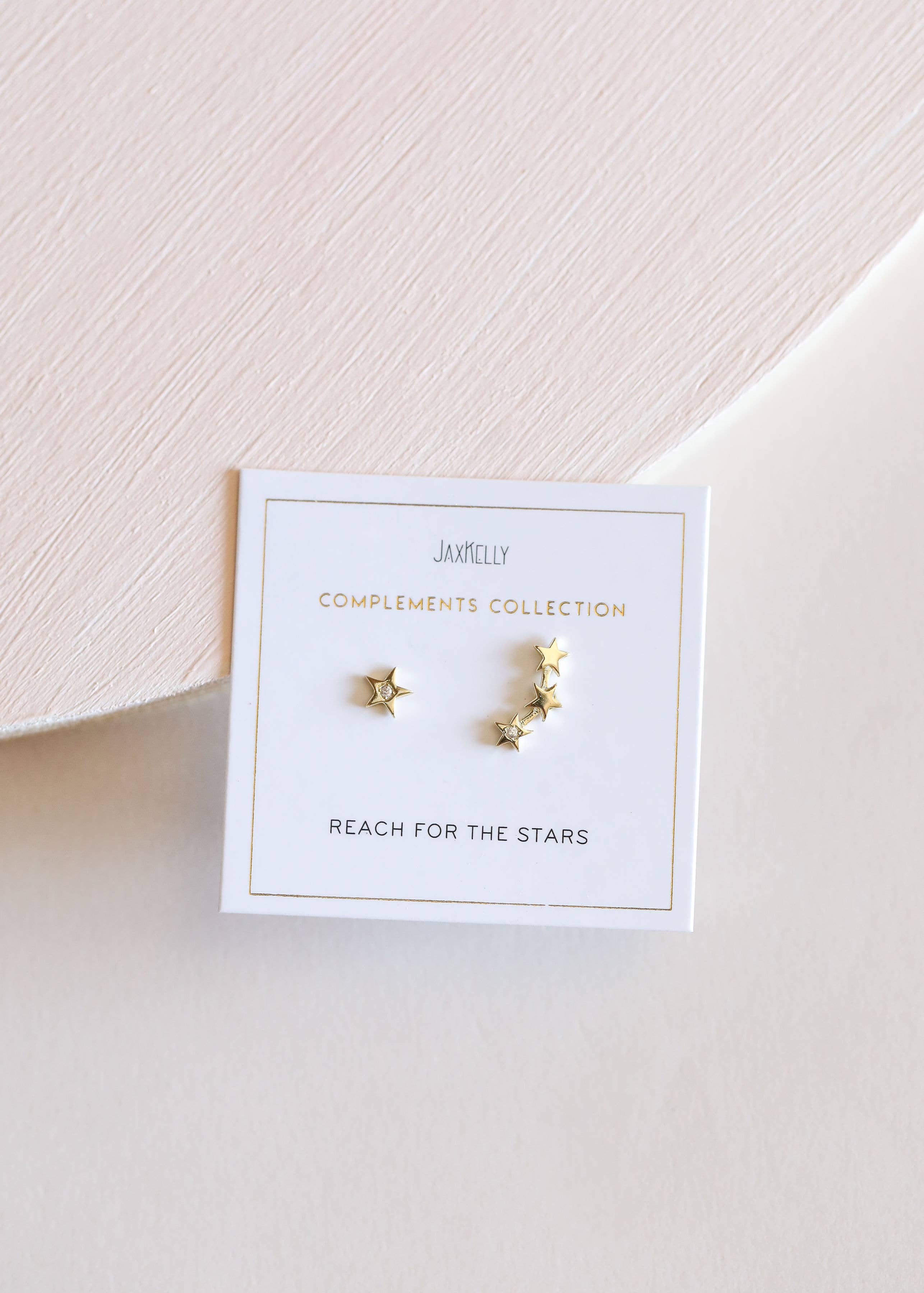 Gold star-shaped earrings on a Jamelly branded card