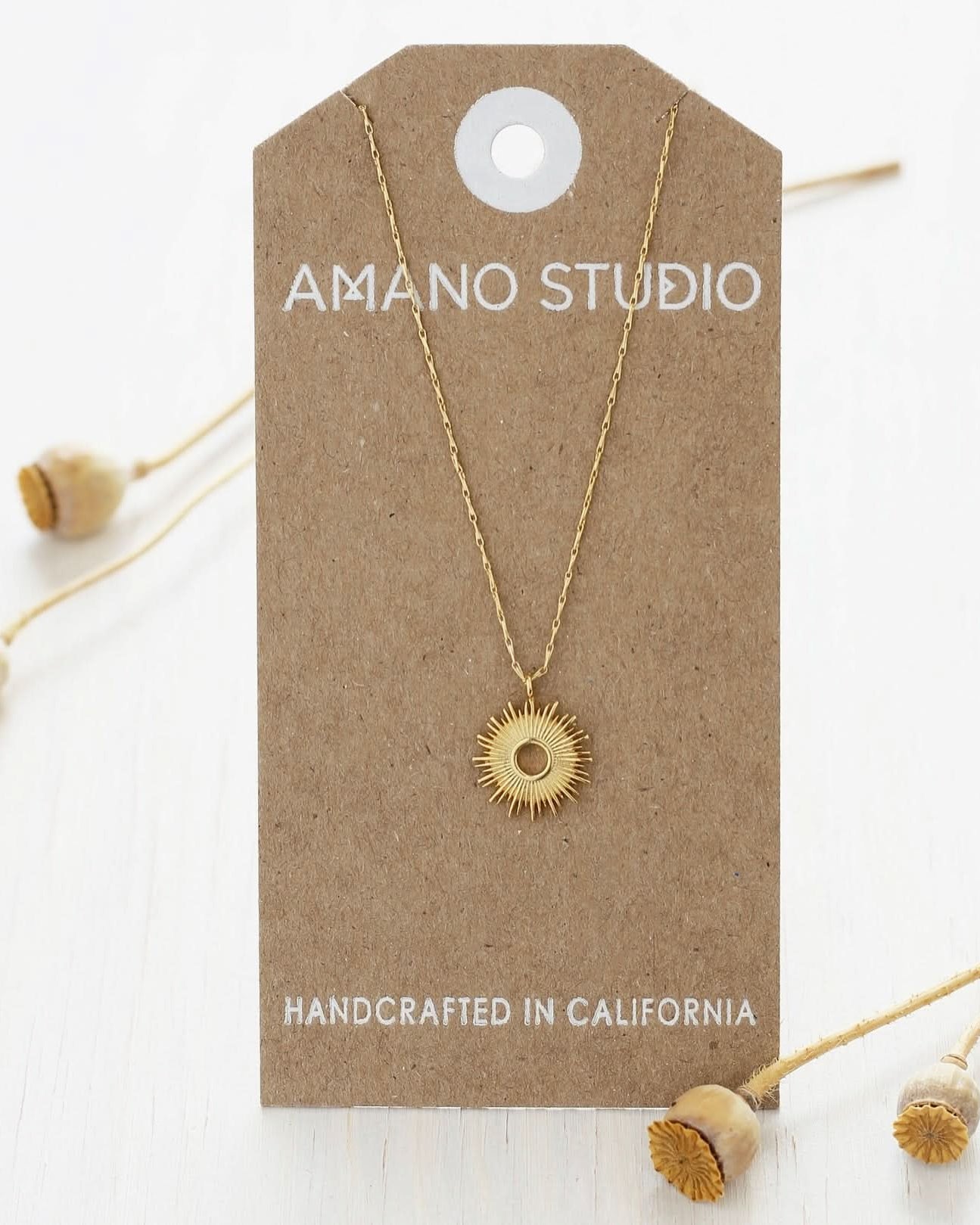 Gold necklace on a 'Amano Studio' branded card