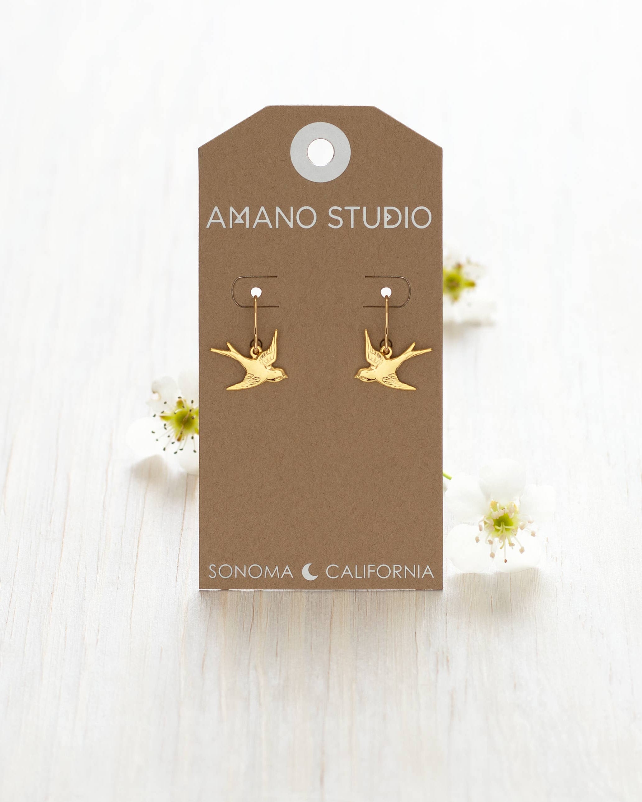 Swallow Bird Drop Earrings displayed on a white wooden background