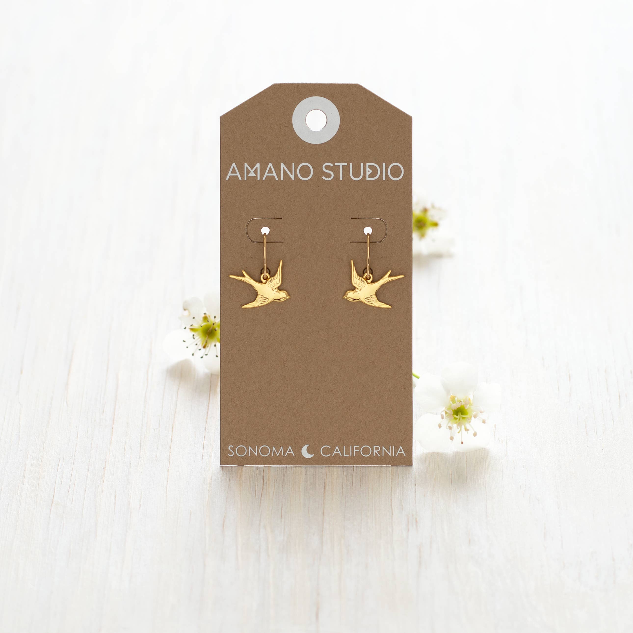 Swallow Bird Drop Earrings displayed on a white wooden background