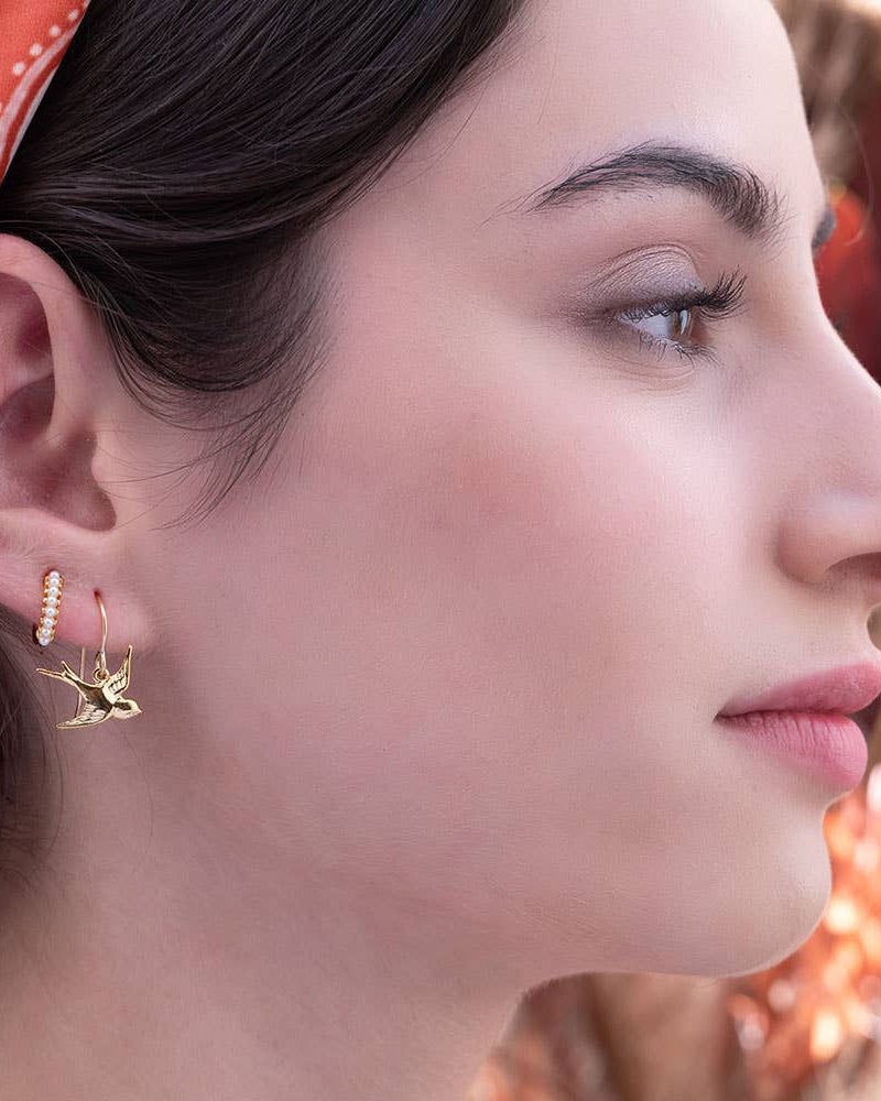 Swallow Bird Drop Earringsglod Close-up of two shiny, gold drop earrings.