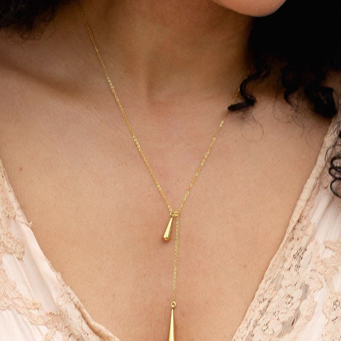 Gold necklace with a pendant worn by a person against a neutral background