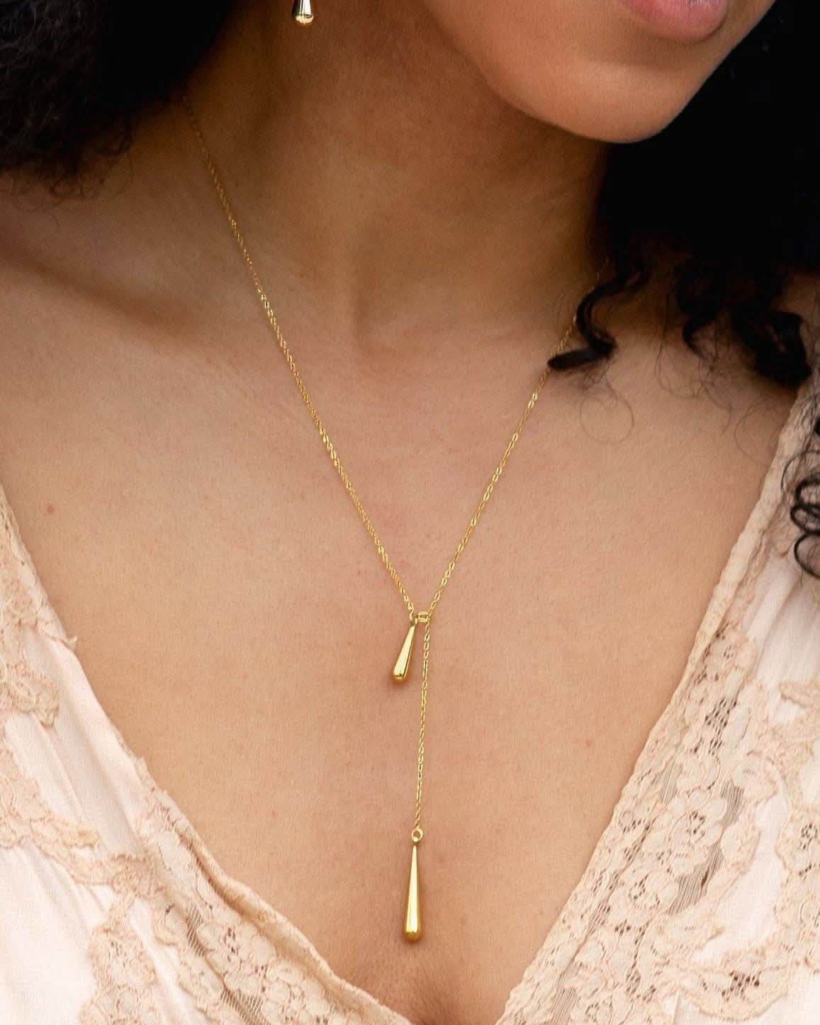 Gold necklace with a pendant worn by a person against a neutral background