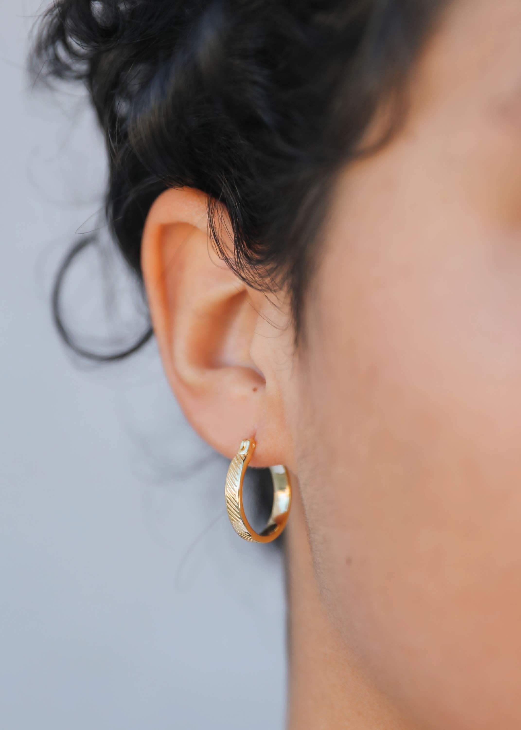Gold hoop earring worn by a person with a blurred background