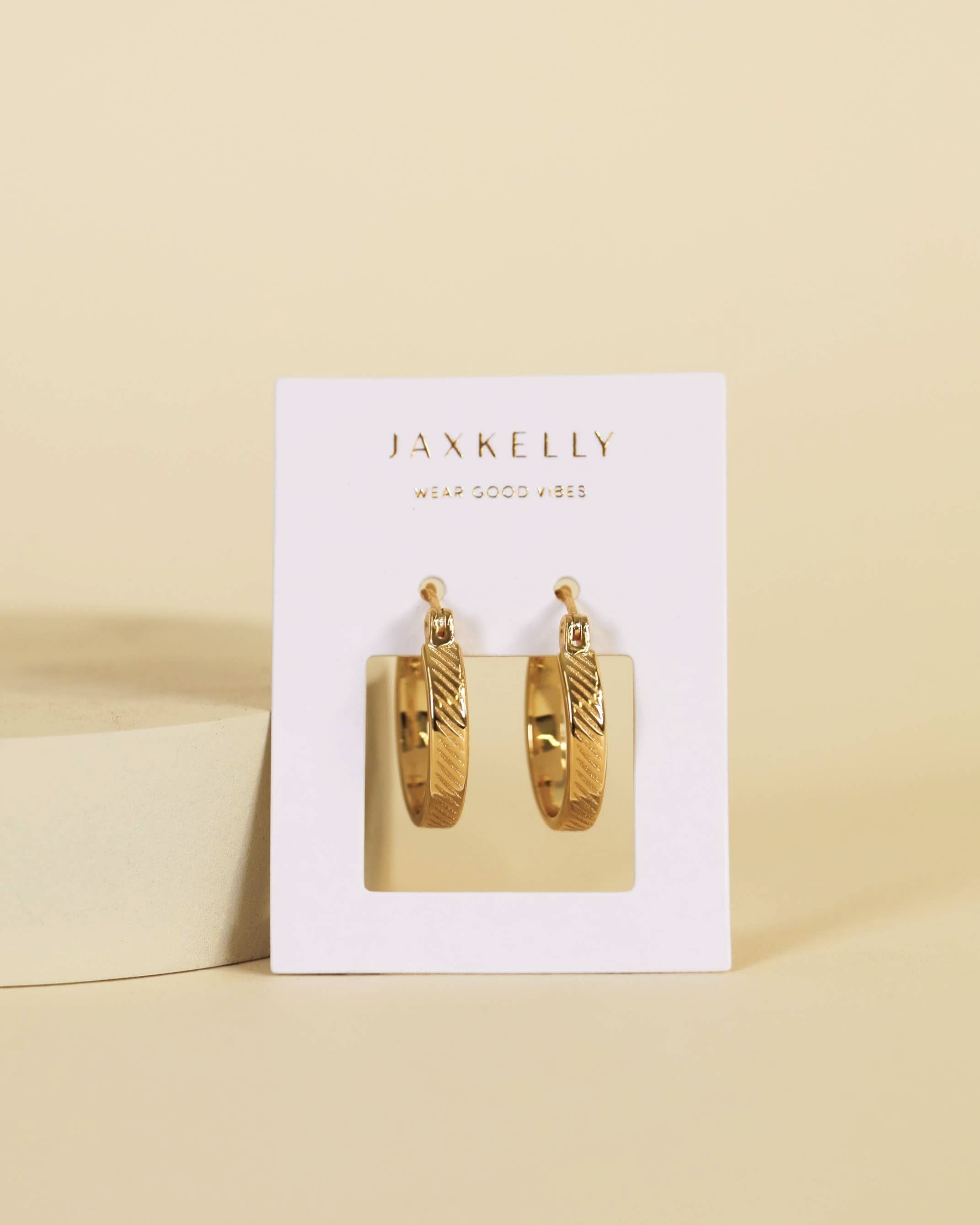 Gold hoop earrings in a Jaxkelly branded box on a beige background