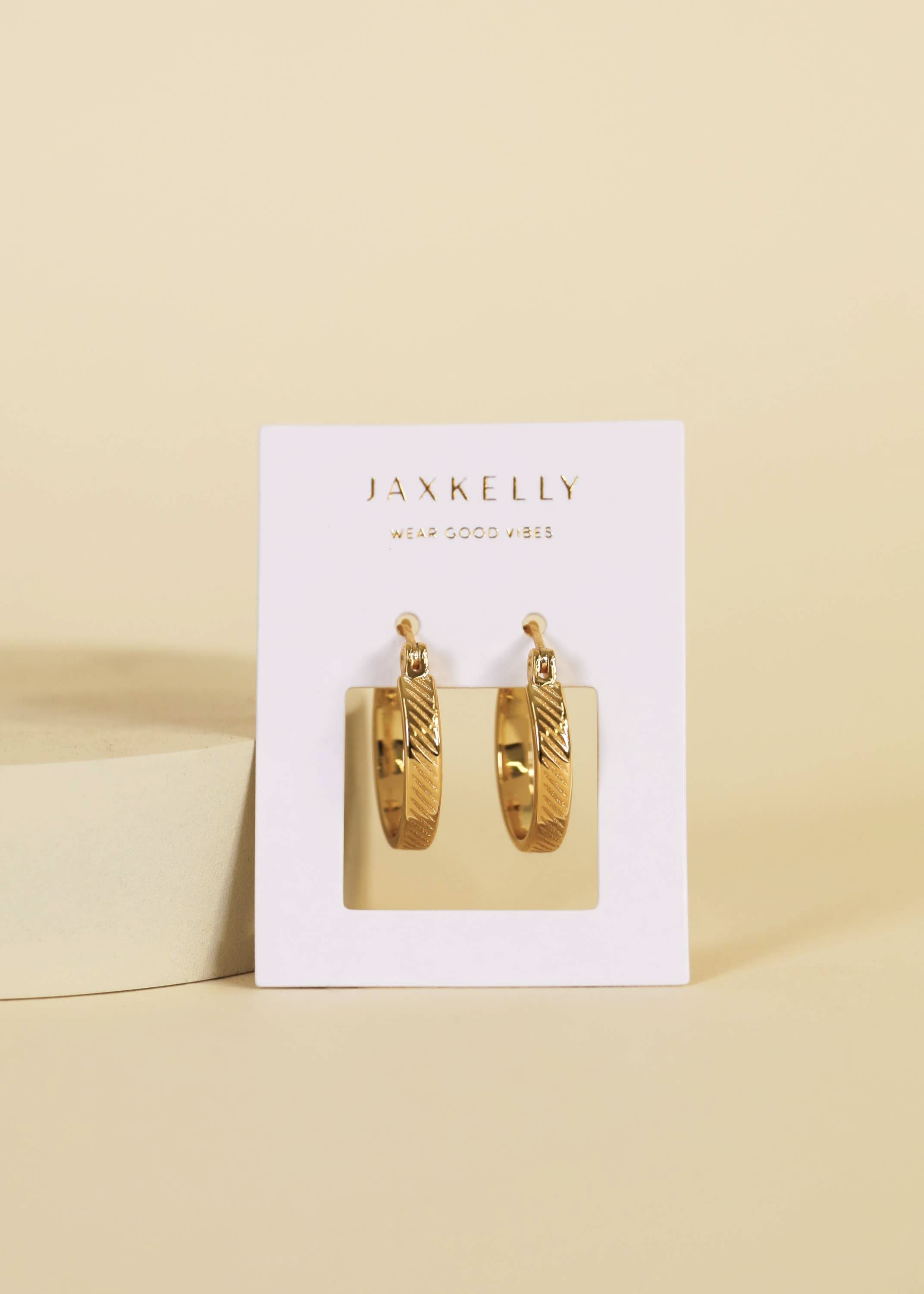 Gold hoop earrings in a Jaxkelly branded box on a beige background