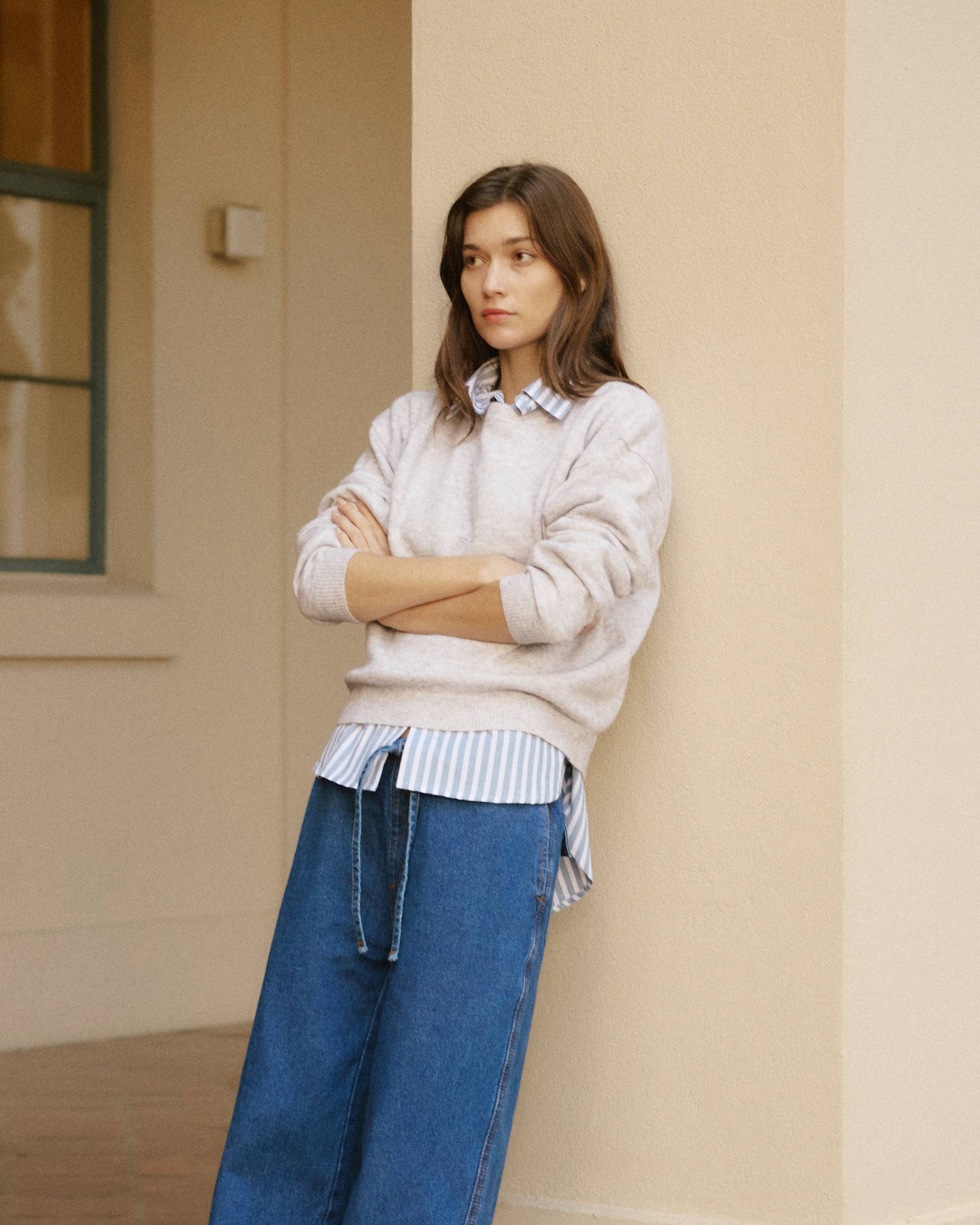 Woman wearing a light sweater and blue jeans standing