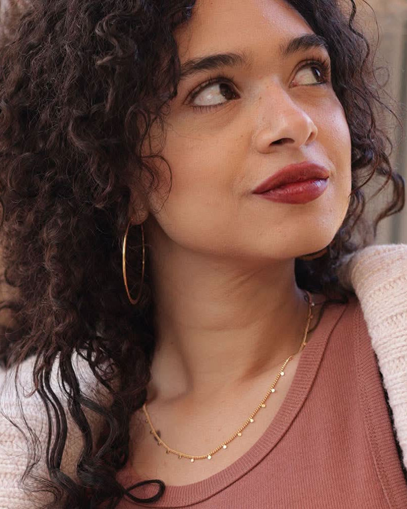 Woman wearing gold chain with tiny gold dots spaced evenly