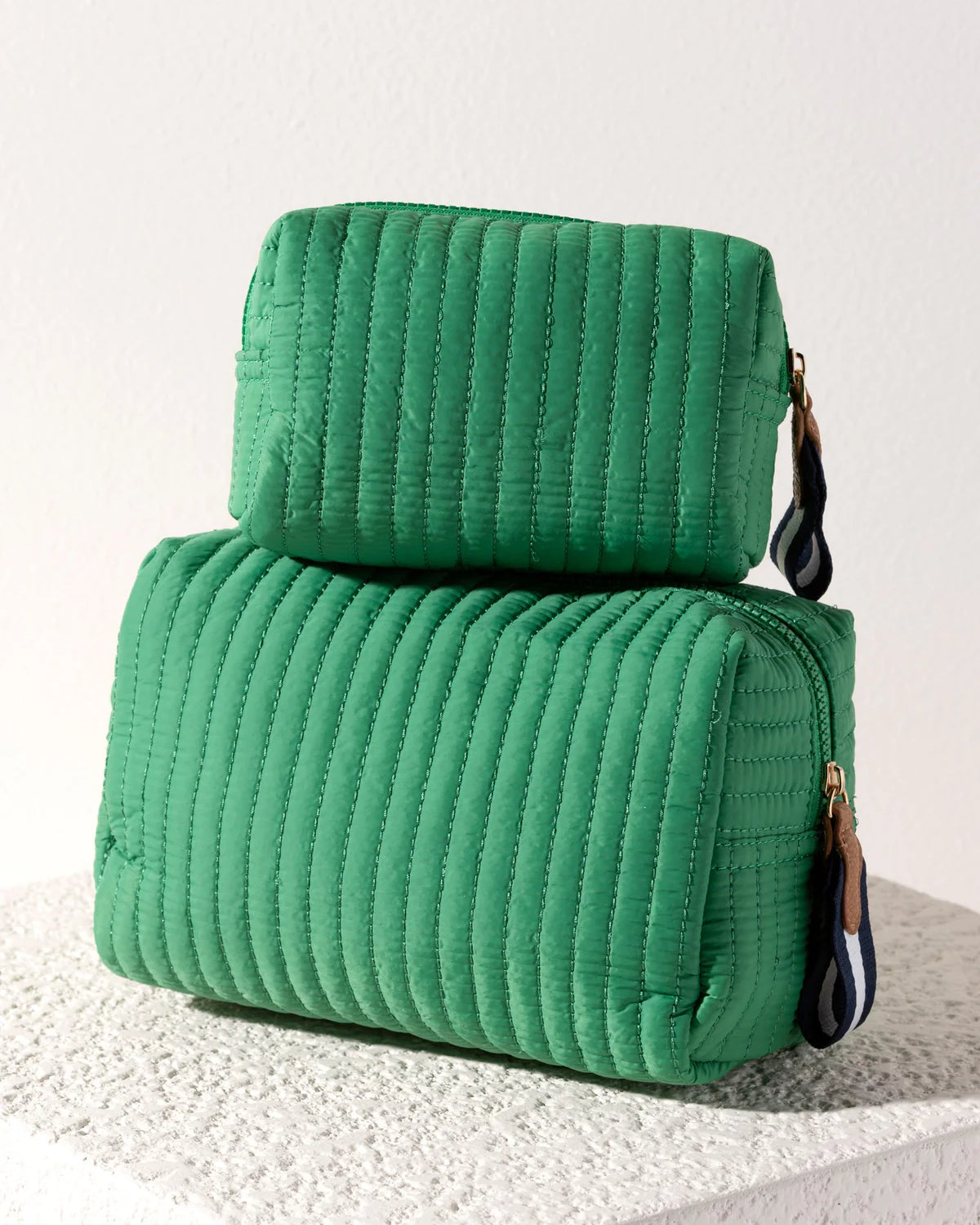 Two green textured bags stacked on a light background