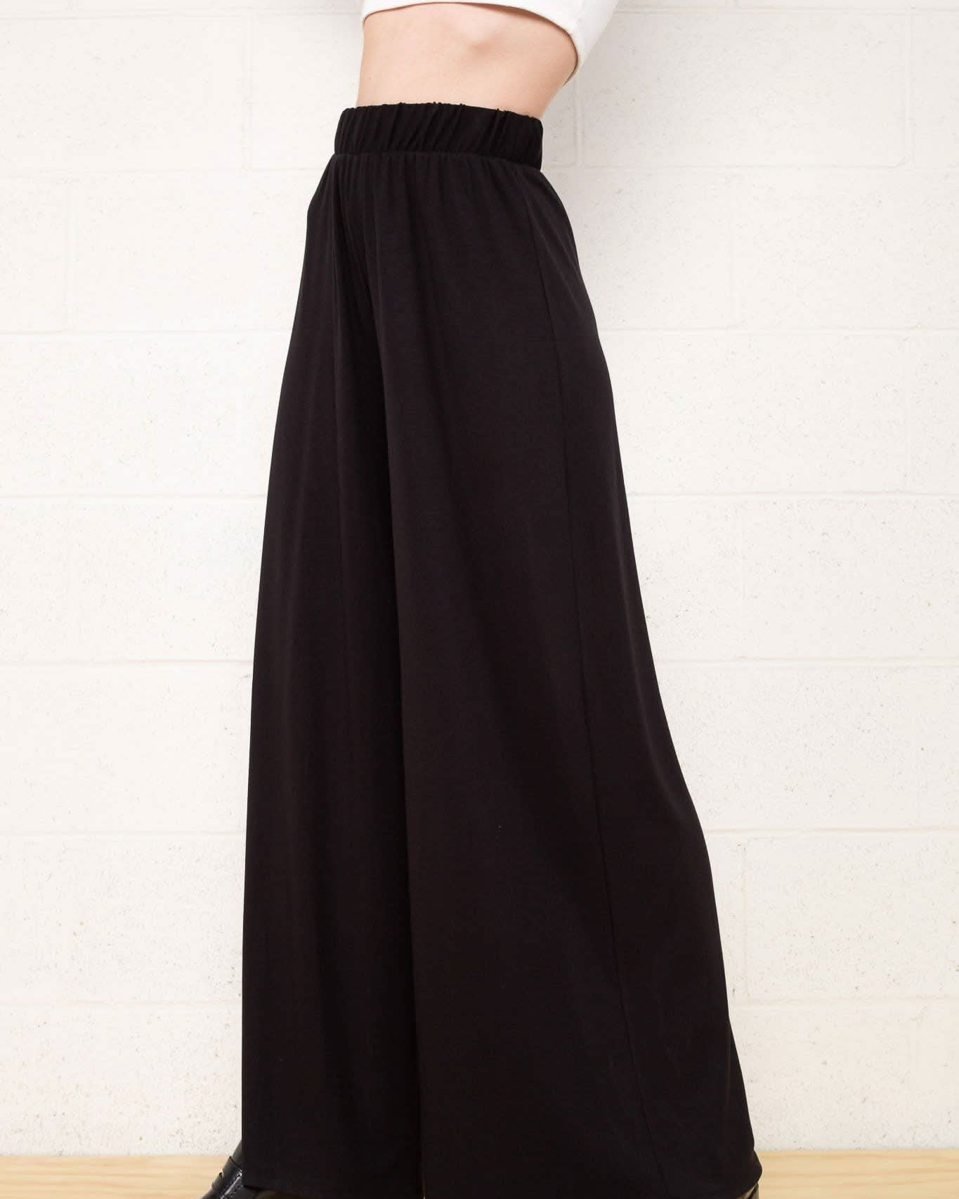 Person wearing black wide-leg pants Made from high-quality materials and designed with a comfortable elastic waist