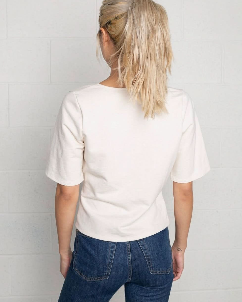 Woman wearing a cream wrap short sleeve shirt with blue jeans