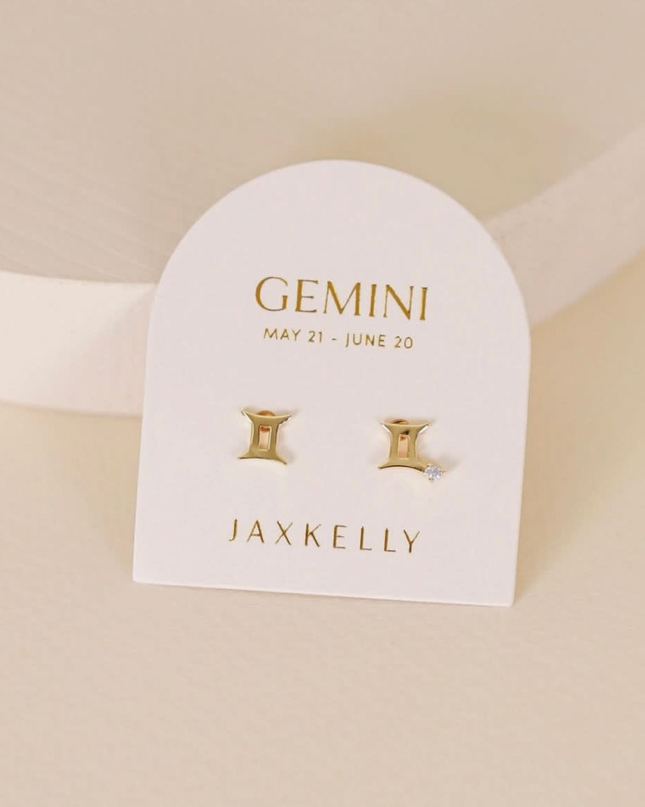 Gold zodiac charm studs in the shape of Gemini astrological sign displayed on earring card