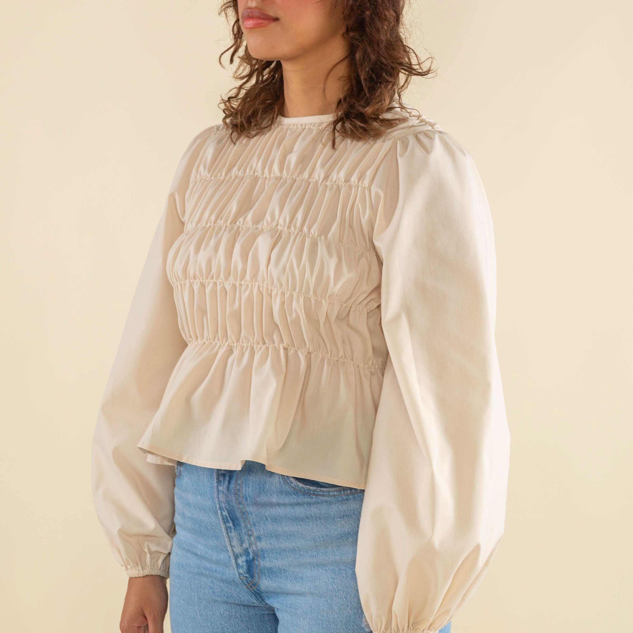 Woman wearing natural cream white color, bubble long sleeve, shirred, peplum style top
