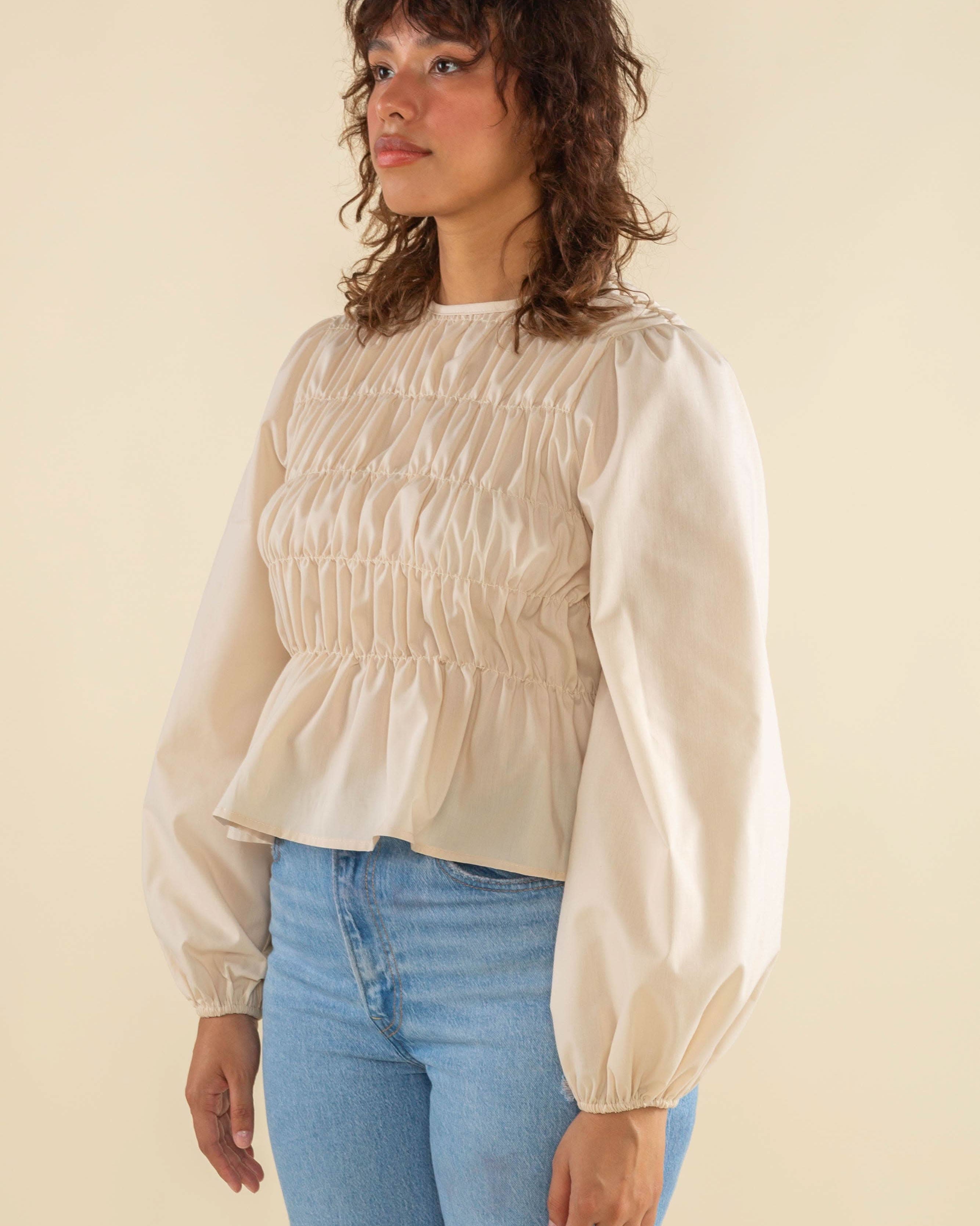 Woman wearing natural cream white color, bubble long sleeve, shirred, peplum style top