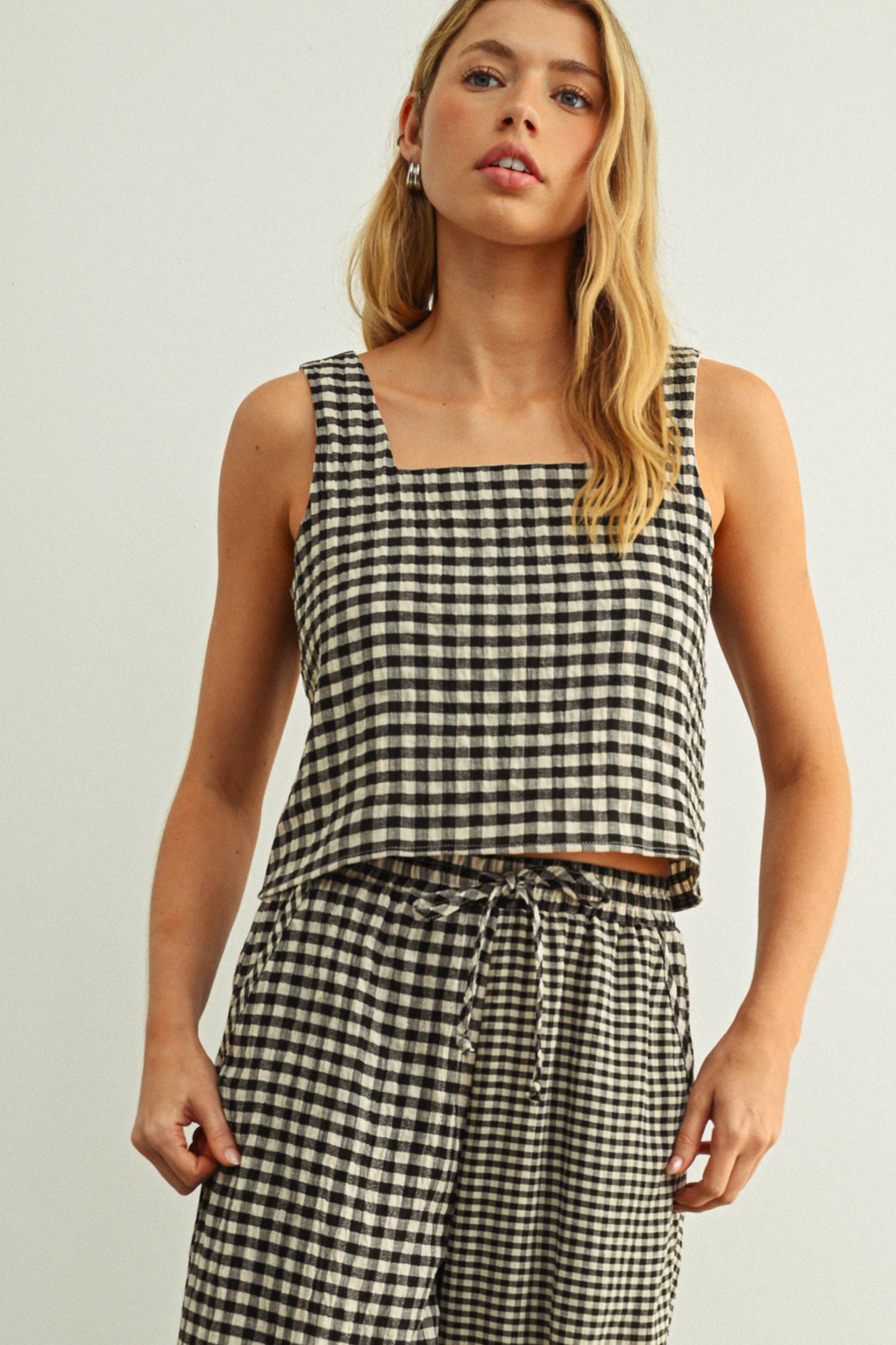 Woman wearing a black and white checkered top and pants on a plain background