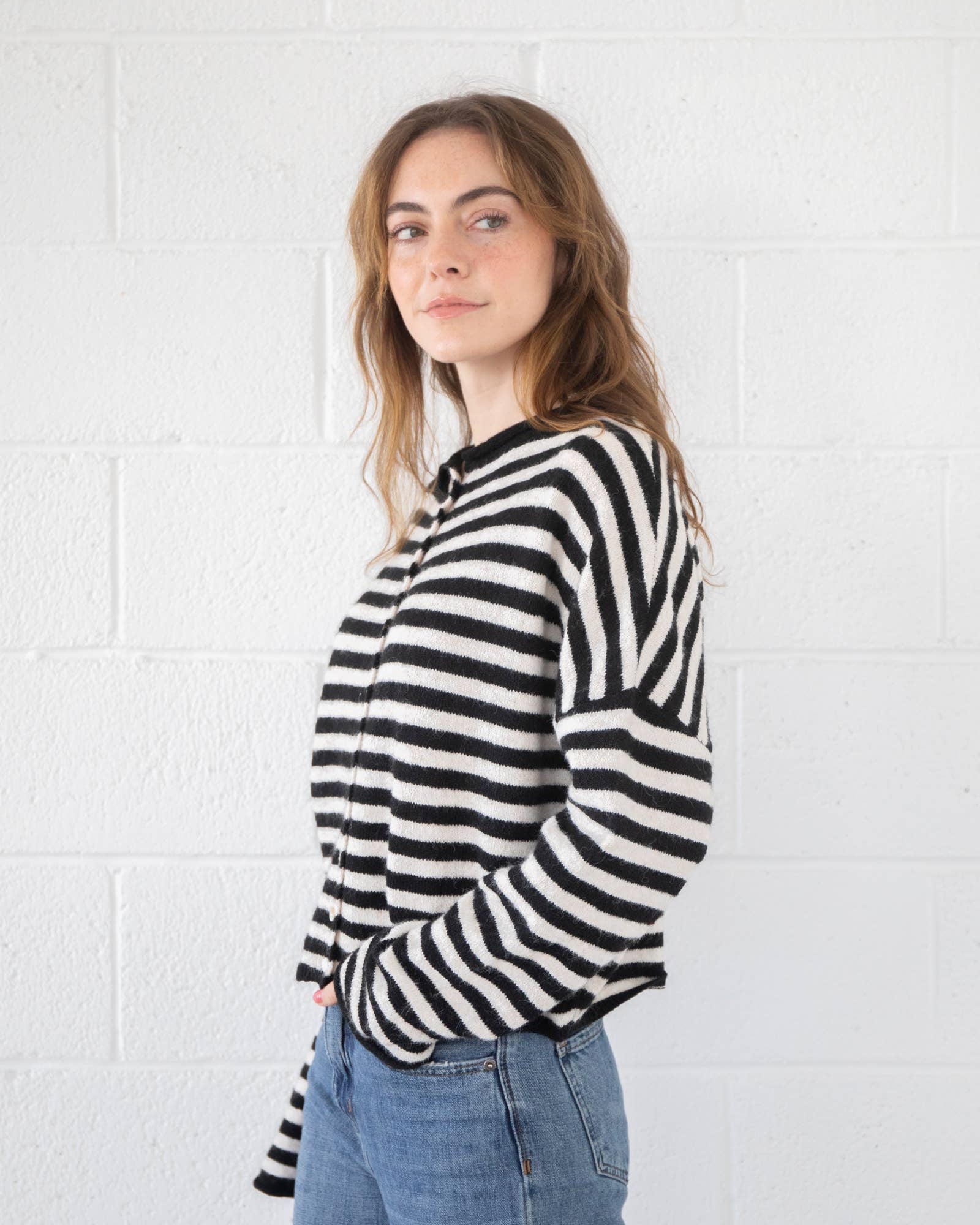 Woman wearing a black and white striped sweater against a white tiled wall