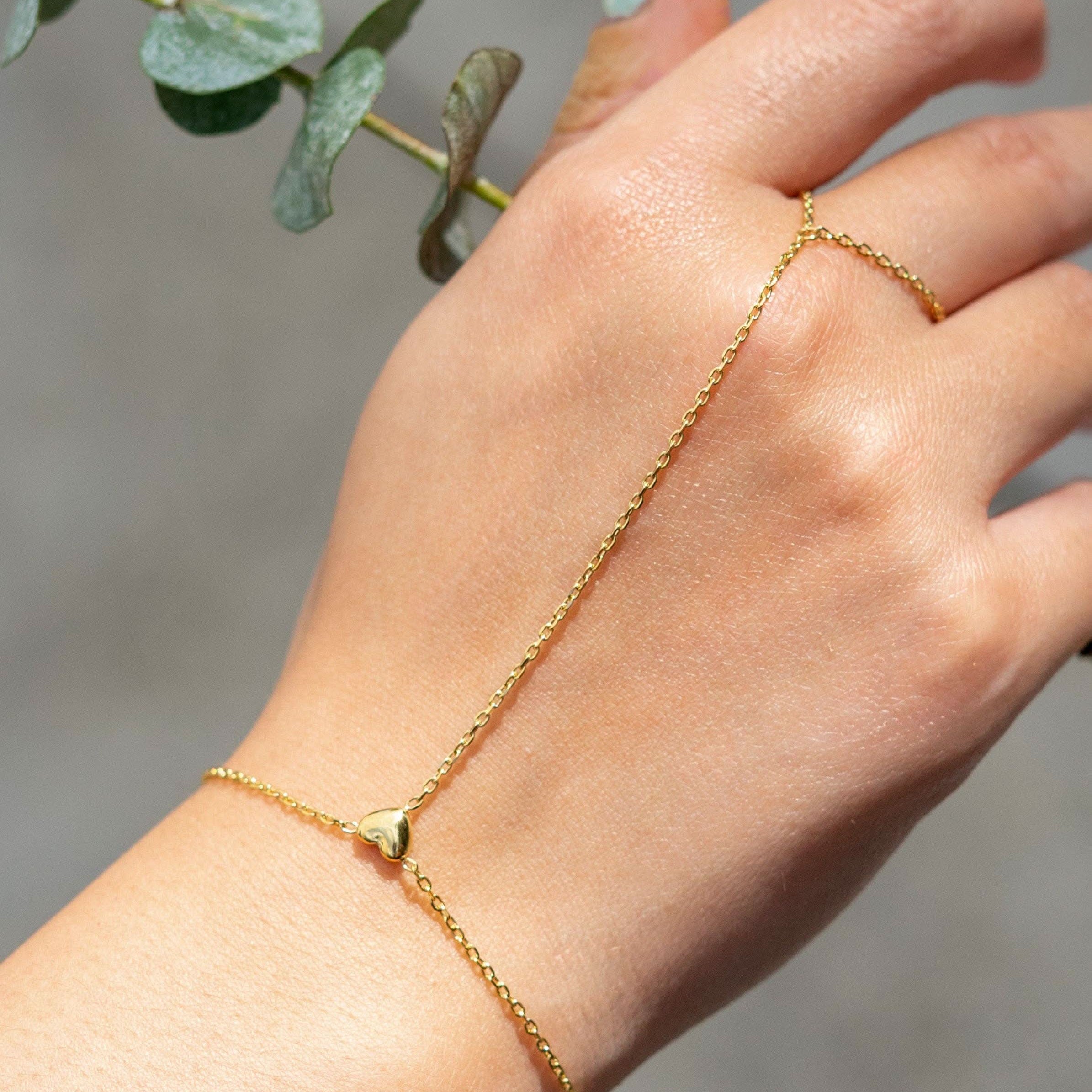 Delicate gold hand chain bracelet connected to a thin ring