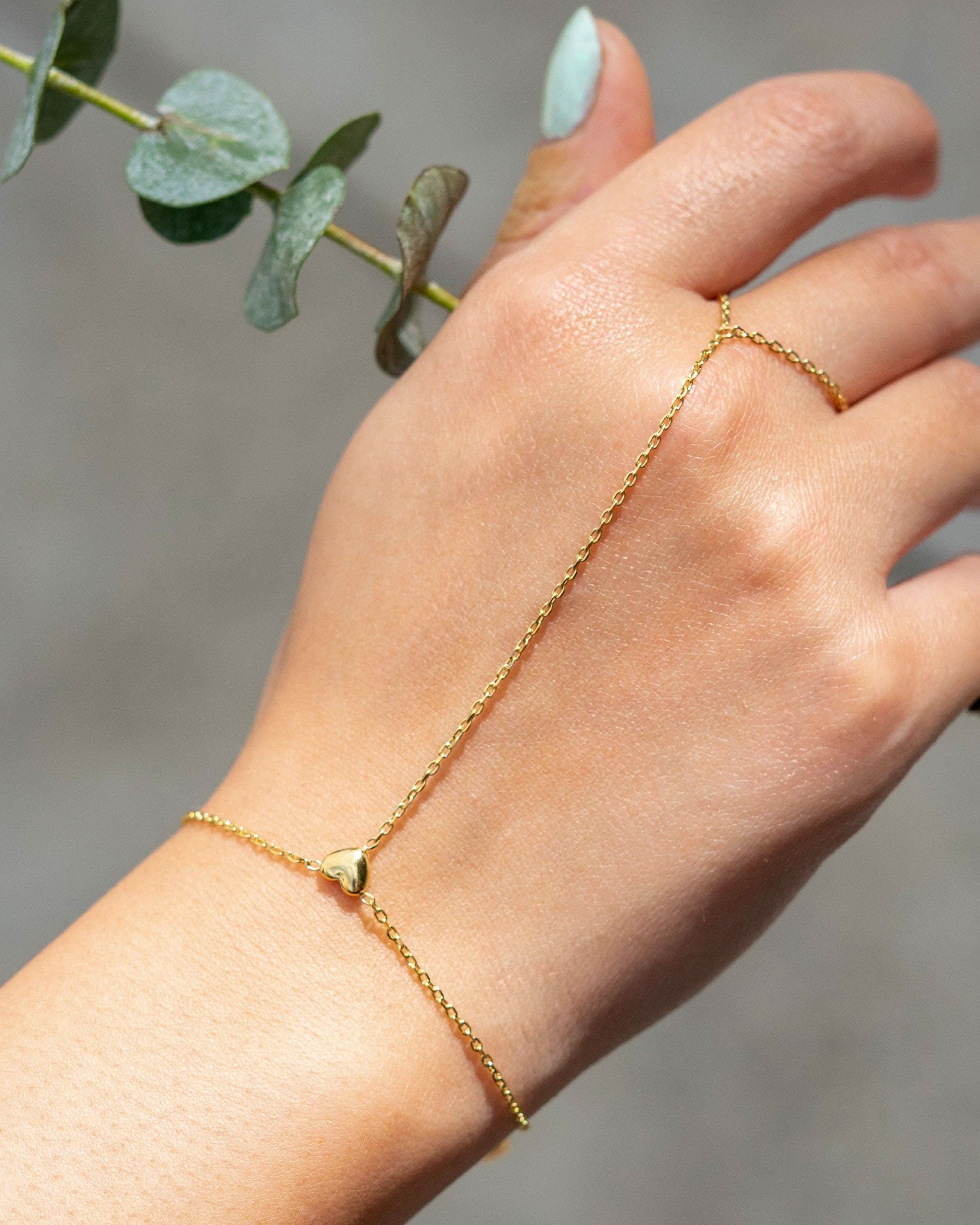 Delicate gold hand chain bracelet connected to a thin ring