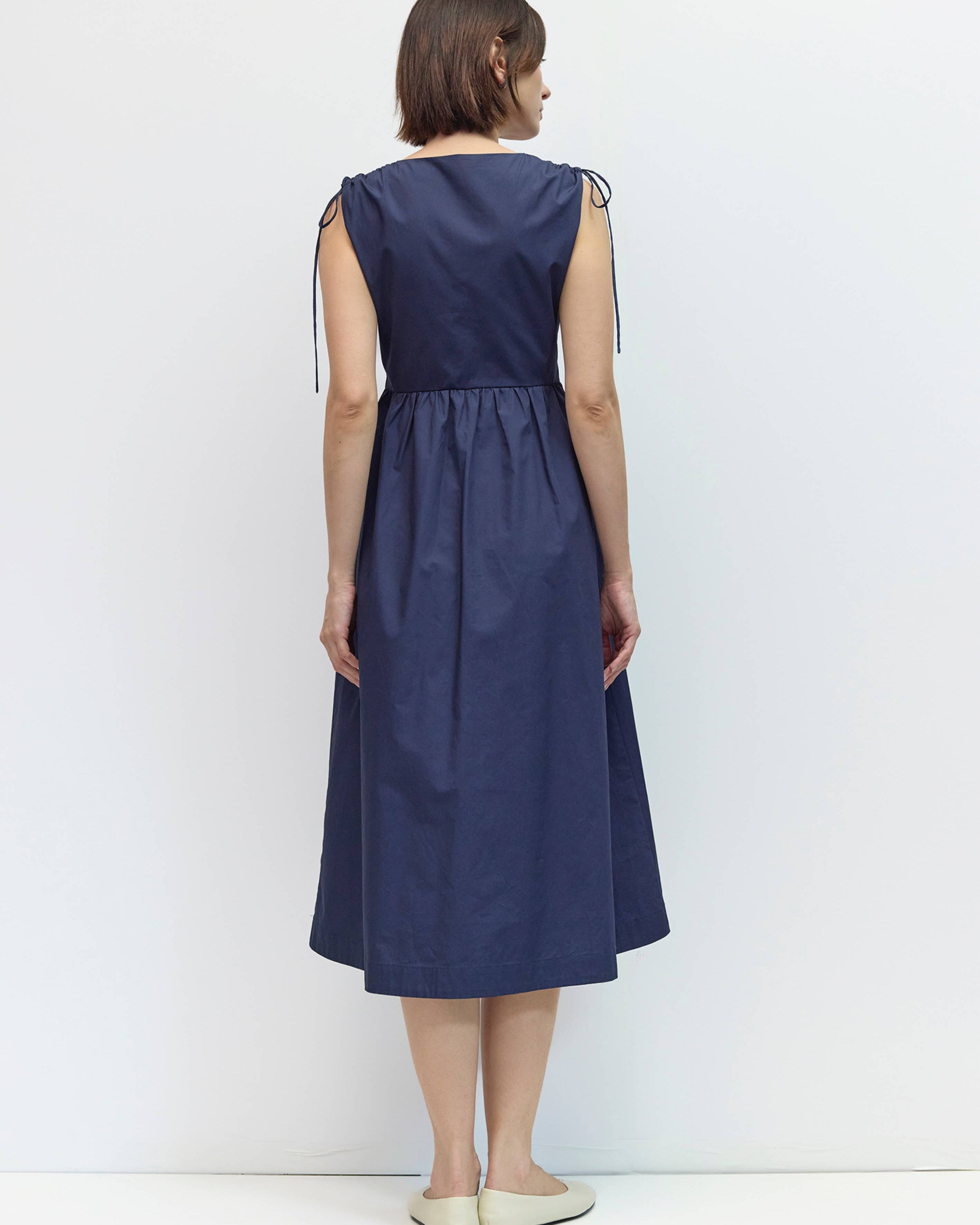 Woman wearing a navy blue dress against a white background