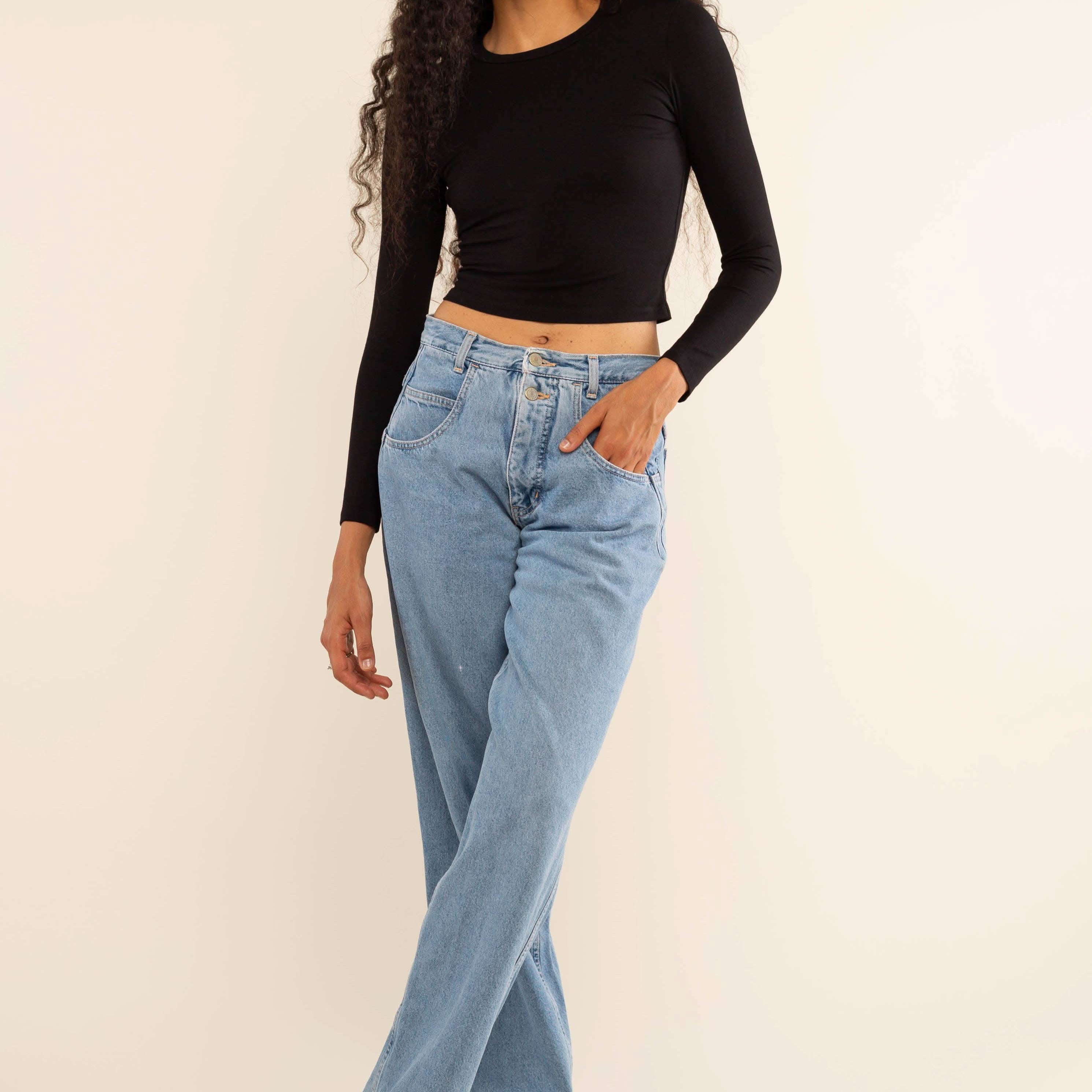 Woman wearing white, long sleeve, tight, crew neck, top with blue jeans