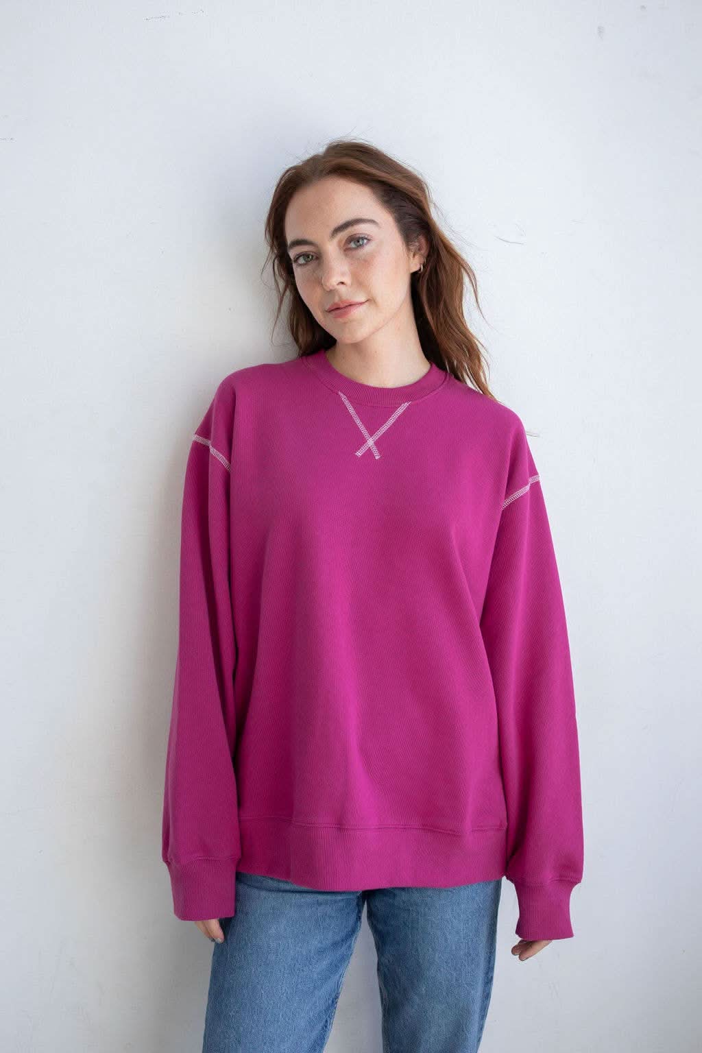 Woman wearing pinkish purple Fuschia pullover with unique stitching details