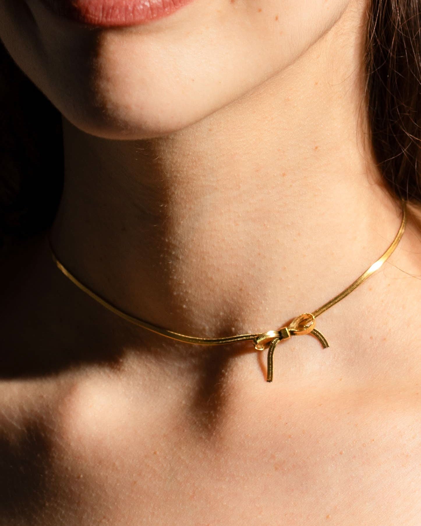 woman wearing gold bow chocker necklace