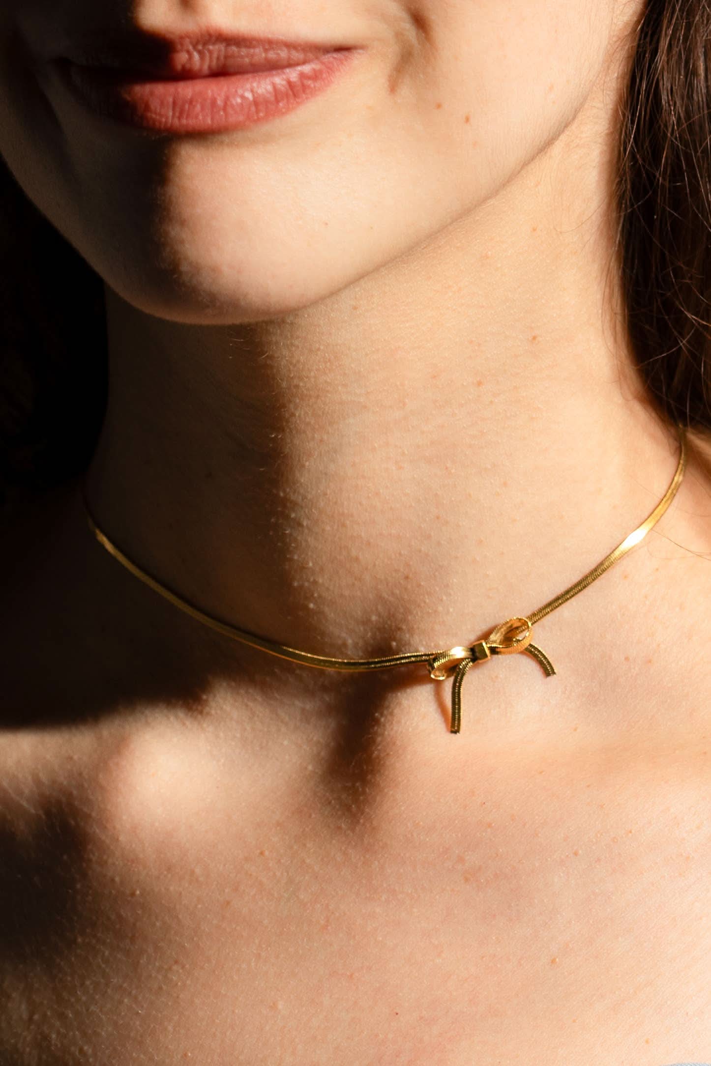 woman wearing gold bow chocker necklace