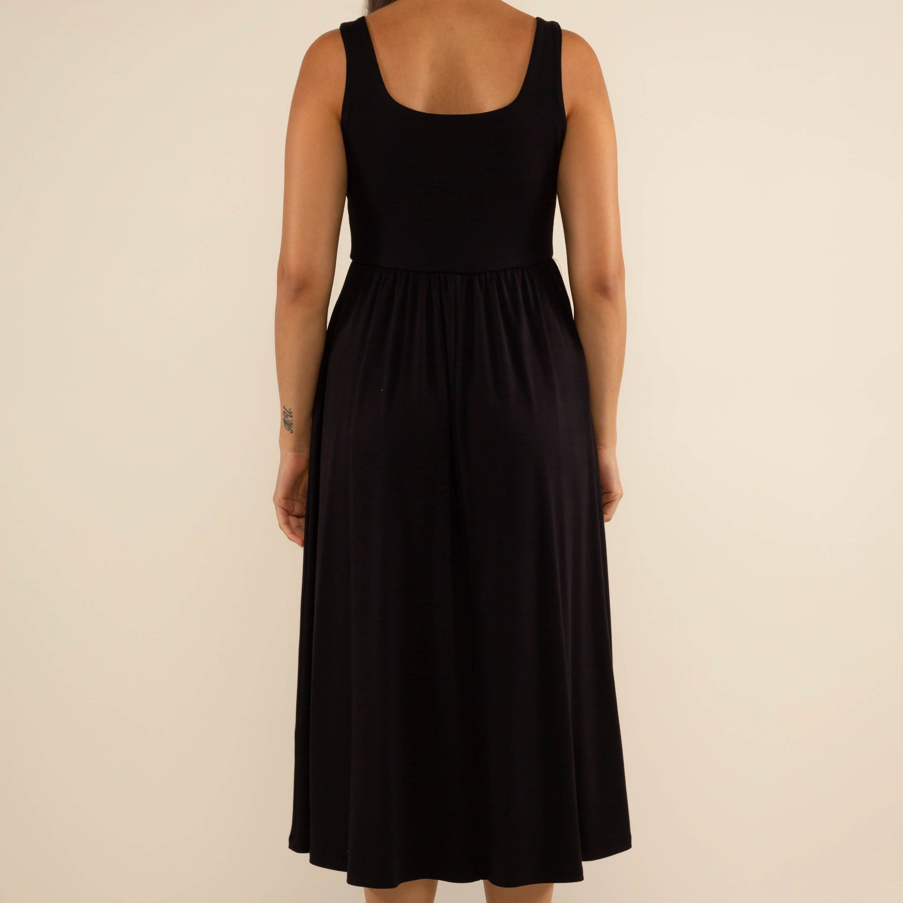 Woman wearing a black sleeveless dress on a beige background