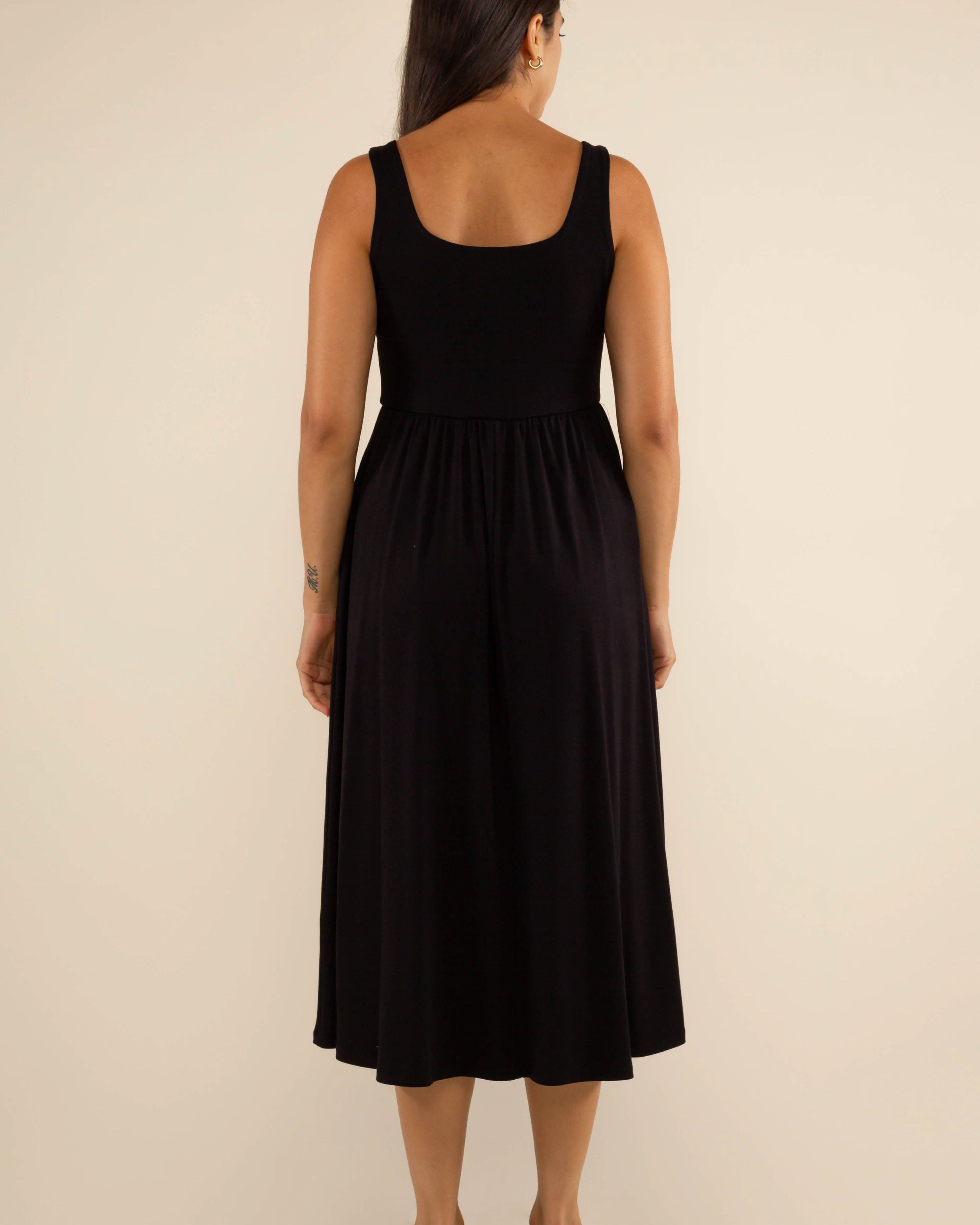 Woman wearing a black sleeveless dress on a beige background