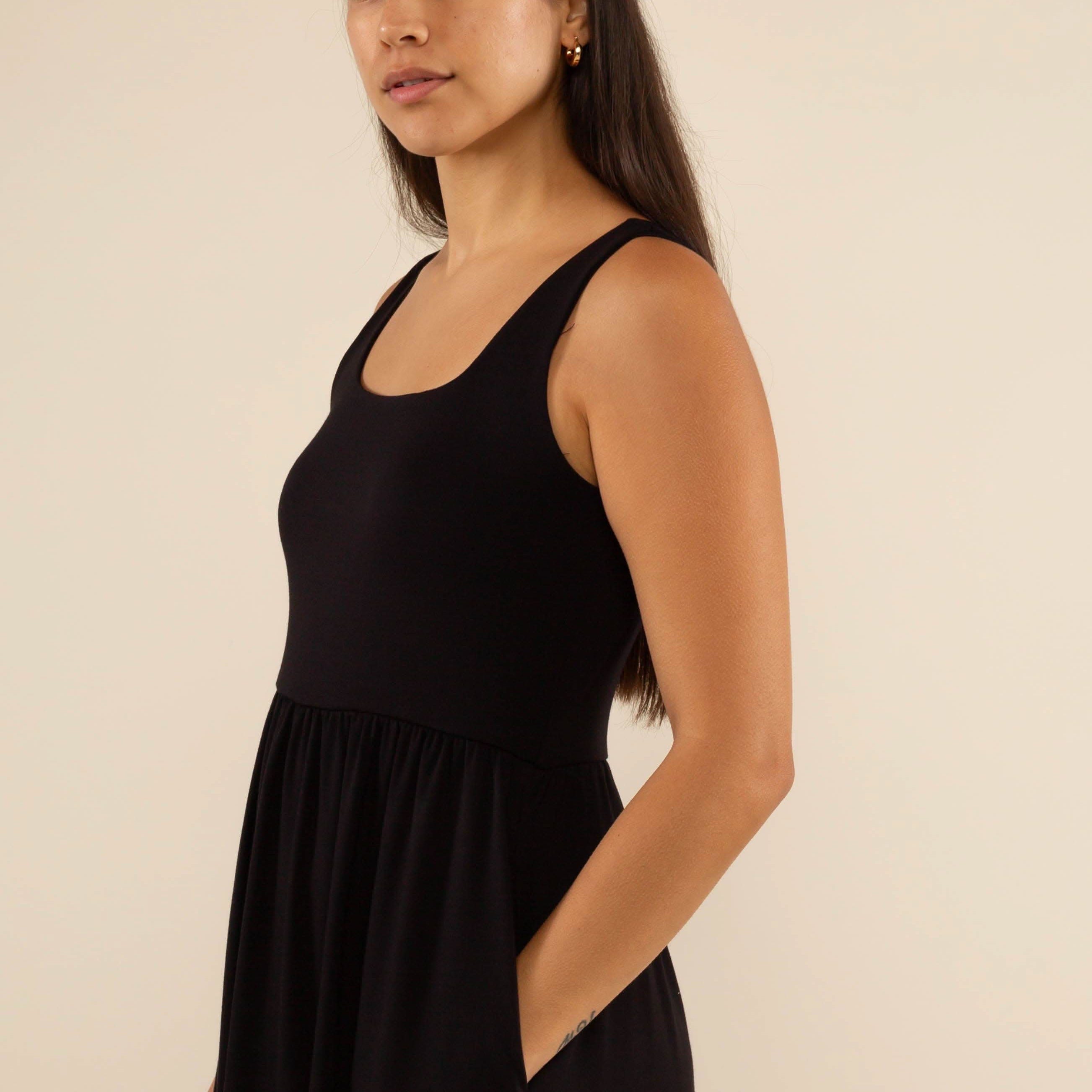 Woman wearing a black sleeveless dress against a beige background