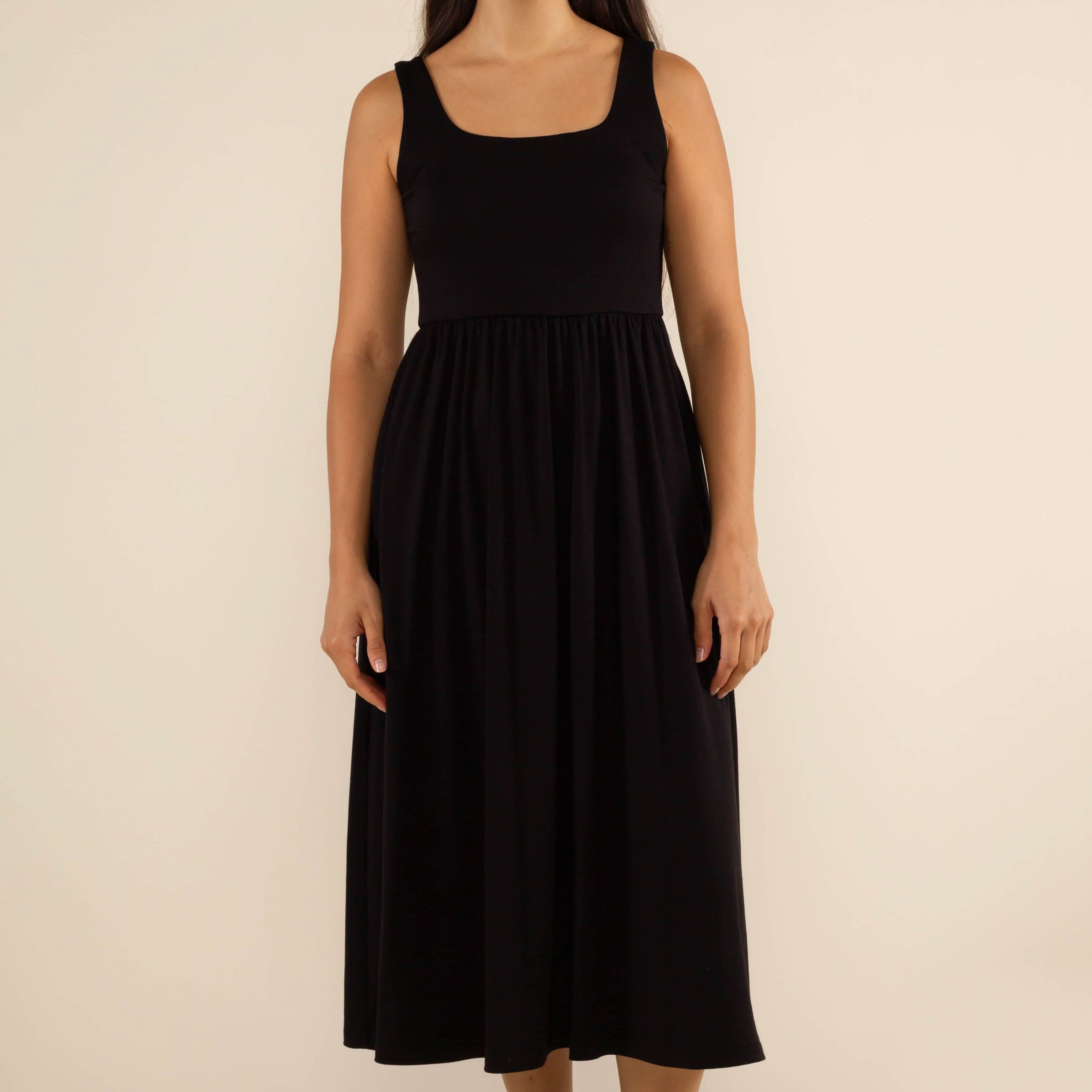 Woman wearing a black sleeveless dress against a beige background