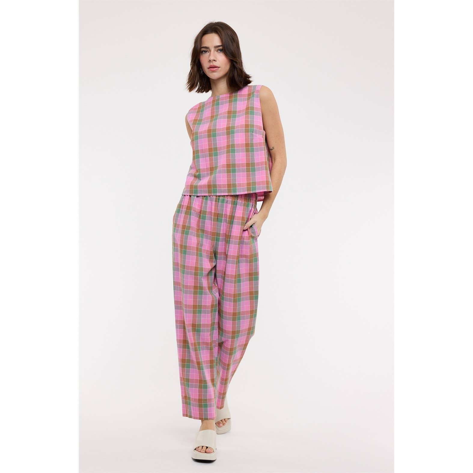 Woman wearing a pink plaid outfit on a white background