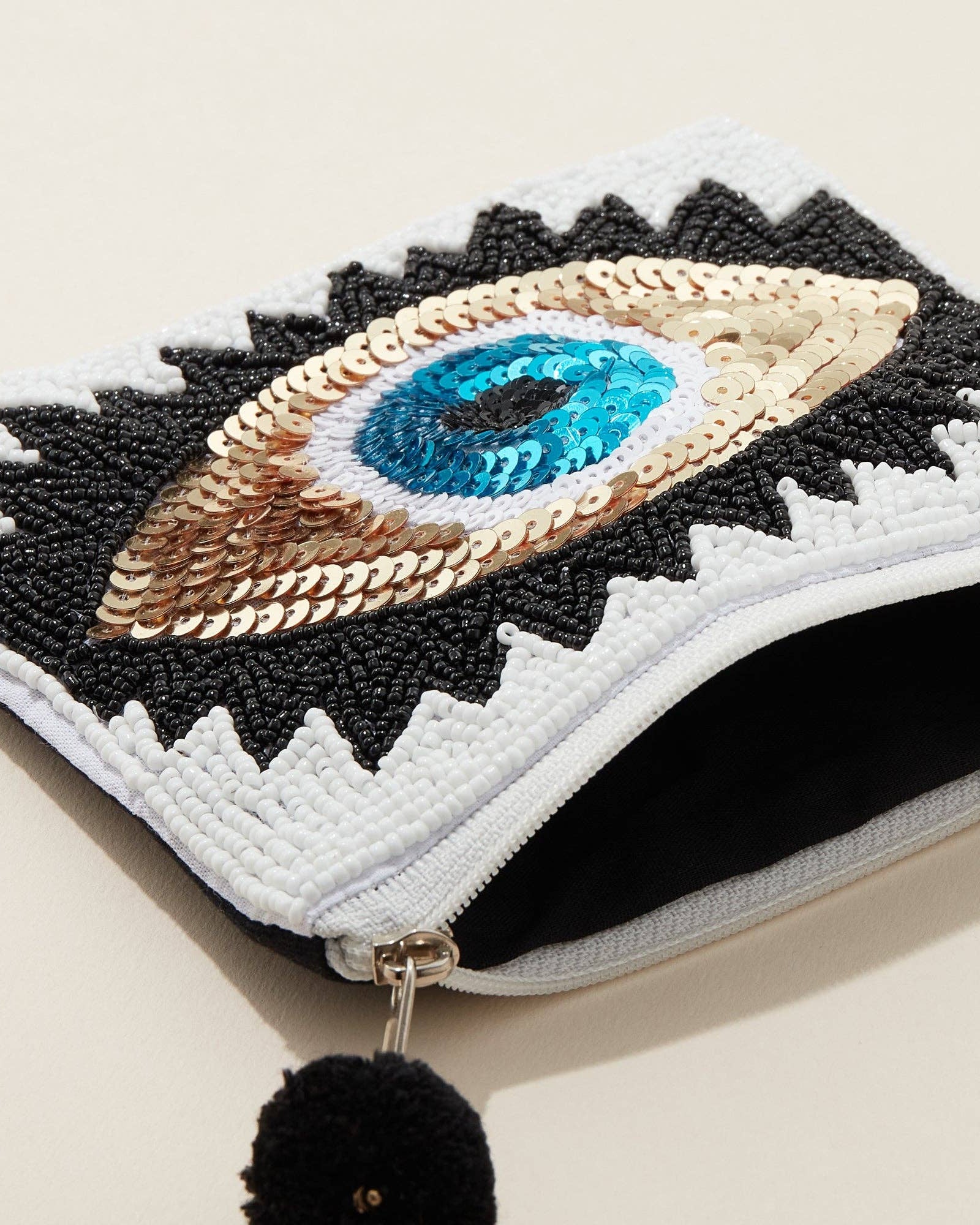 Embroidered pouch with eye design on a beige background