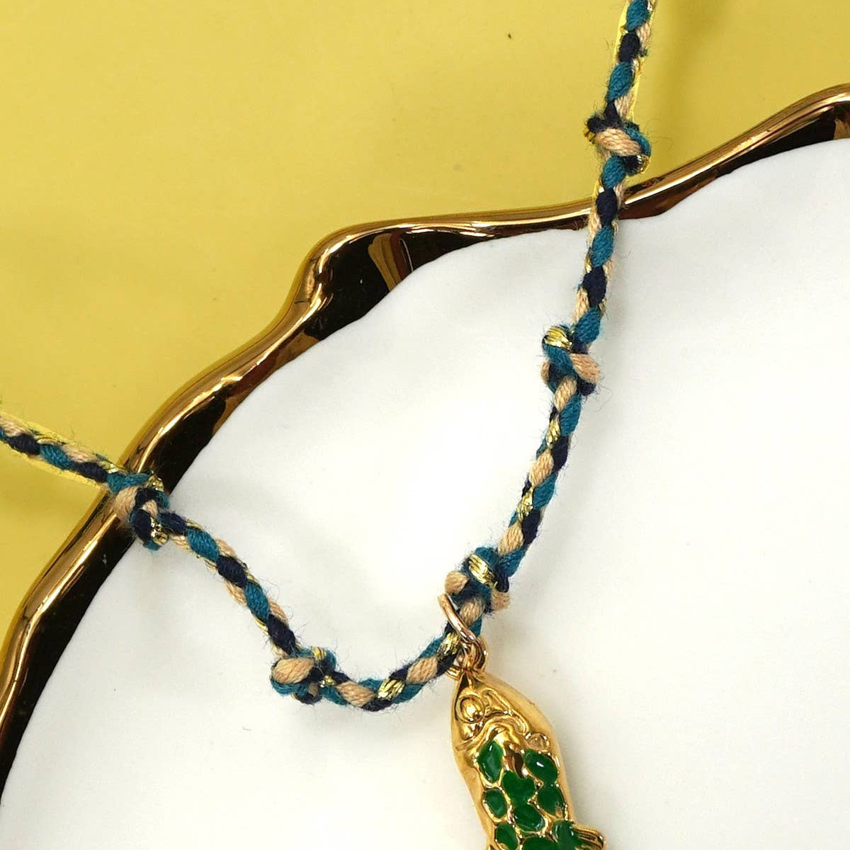 Necklace with green fish pendant on a yellow background