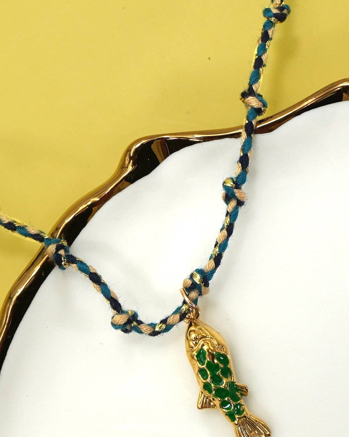 Necklace with green fish pendant on a yellow background