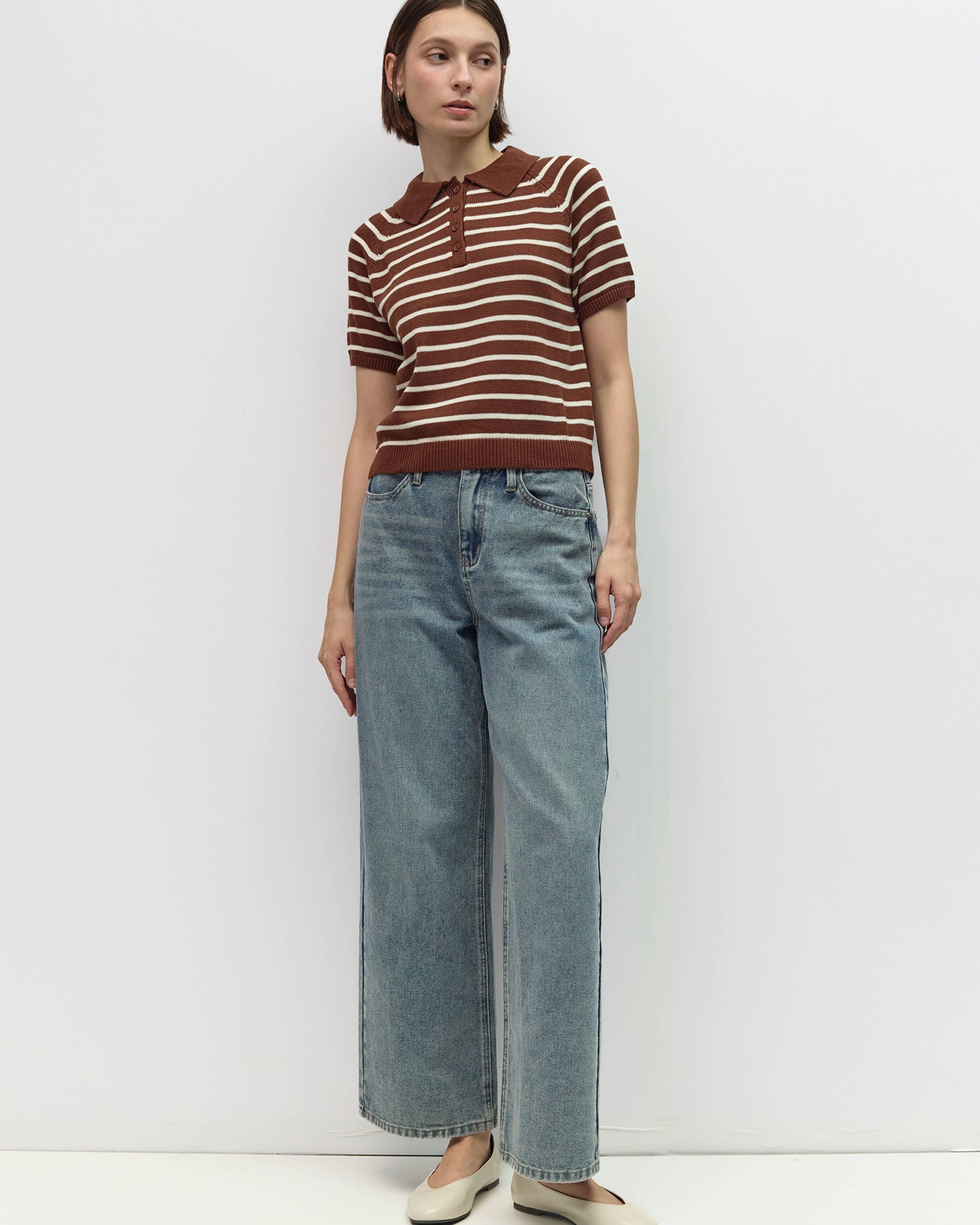 Person wearing a brown and white striped shirt and blue jeans on a white background
