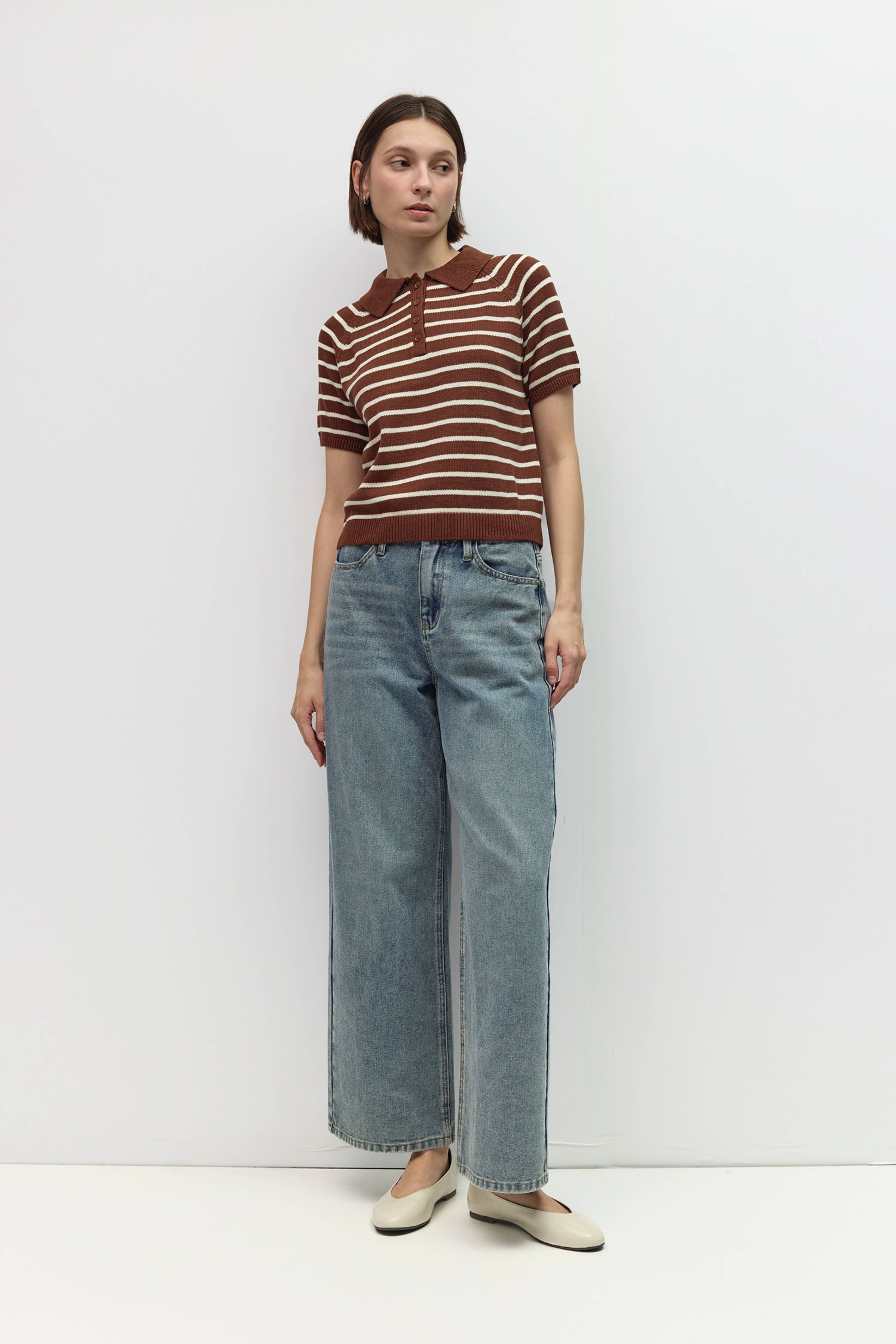 Person wearing a brown and white striped shirt and blue jeans on a white background