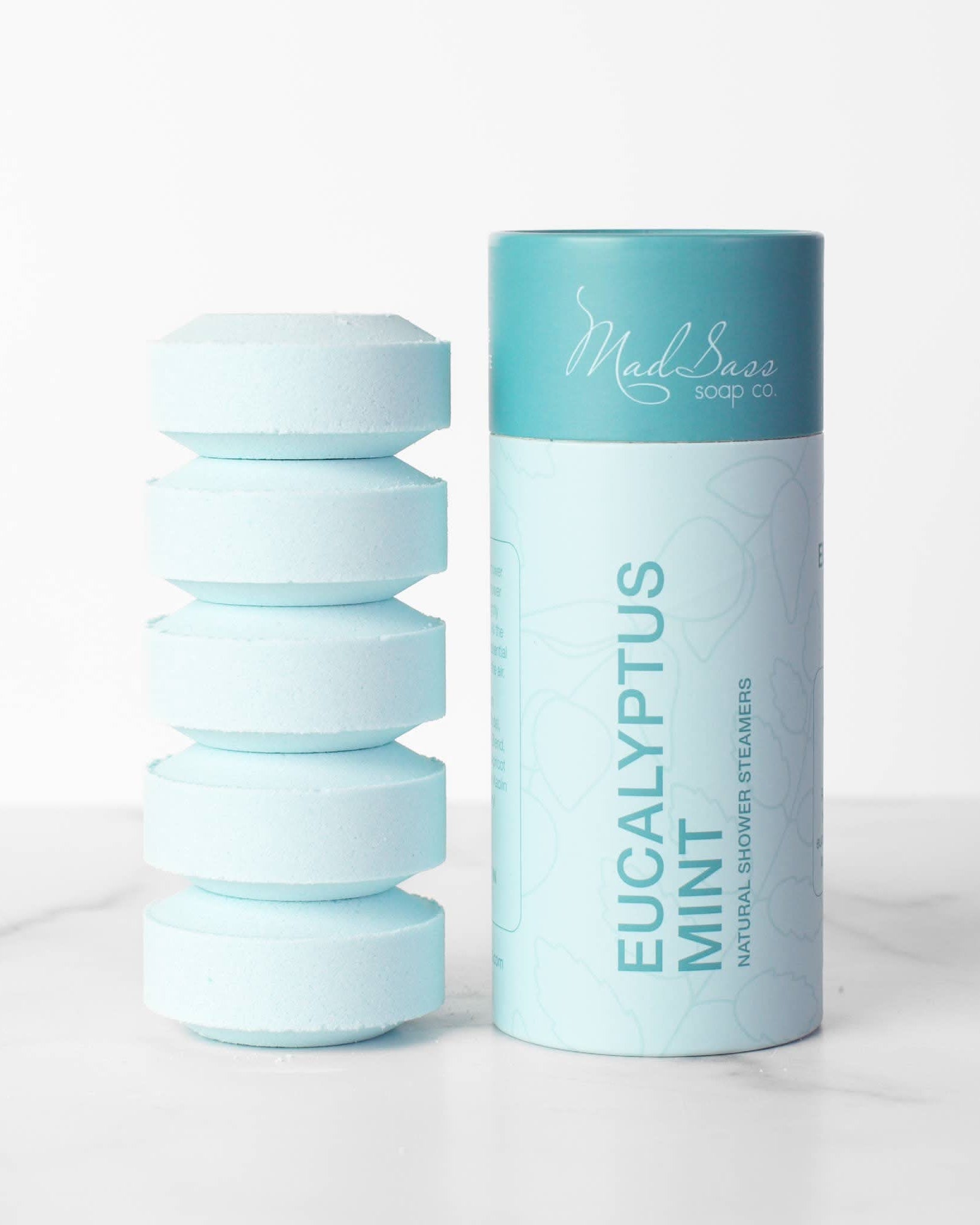 Stacked blue eucalyptus mint shower steamer tablets next to packaging