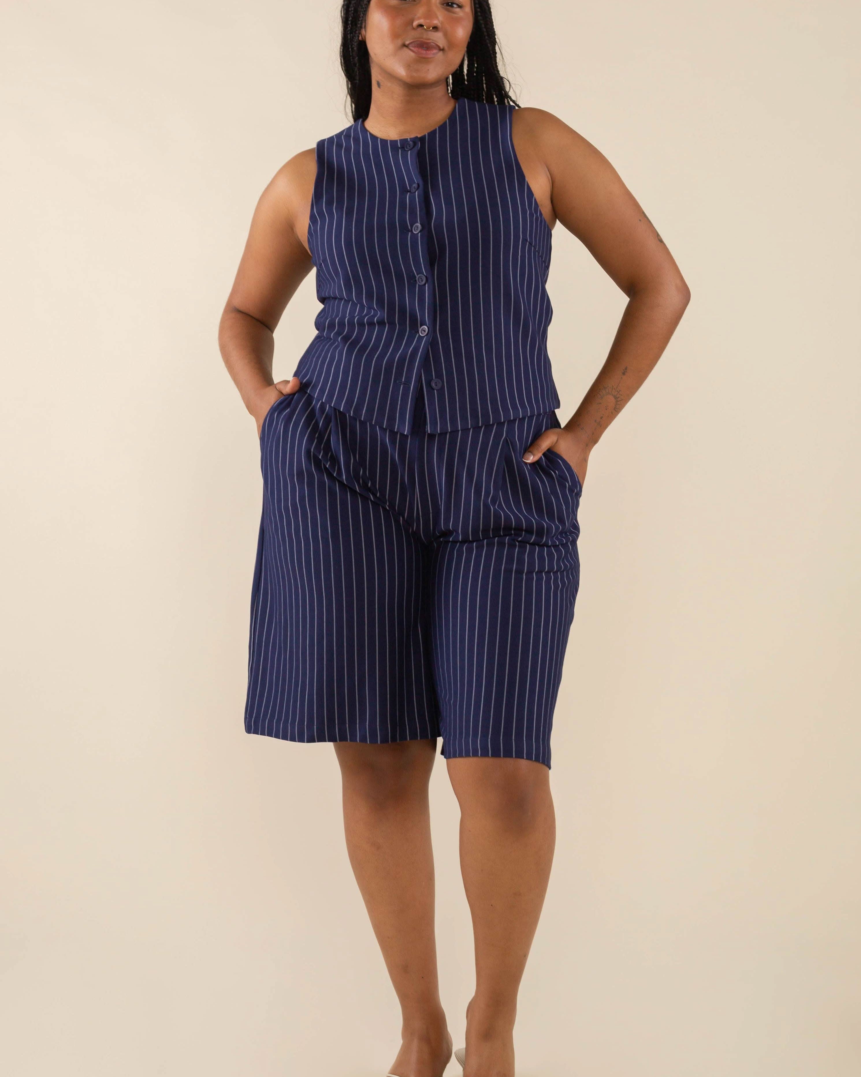 Woman wearing navy blue high neck vest with cream pinstripes. Vest has navy blue buttons all the way down