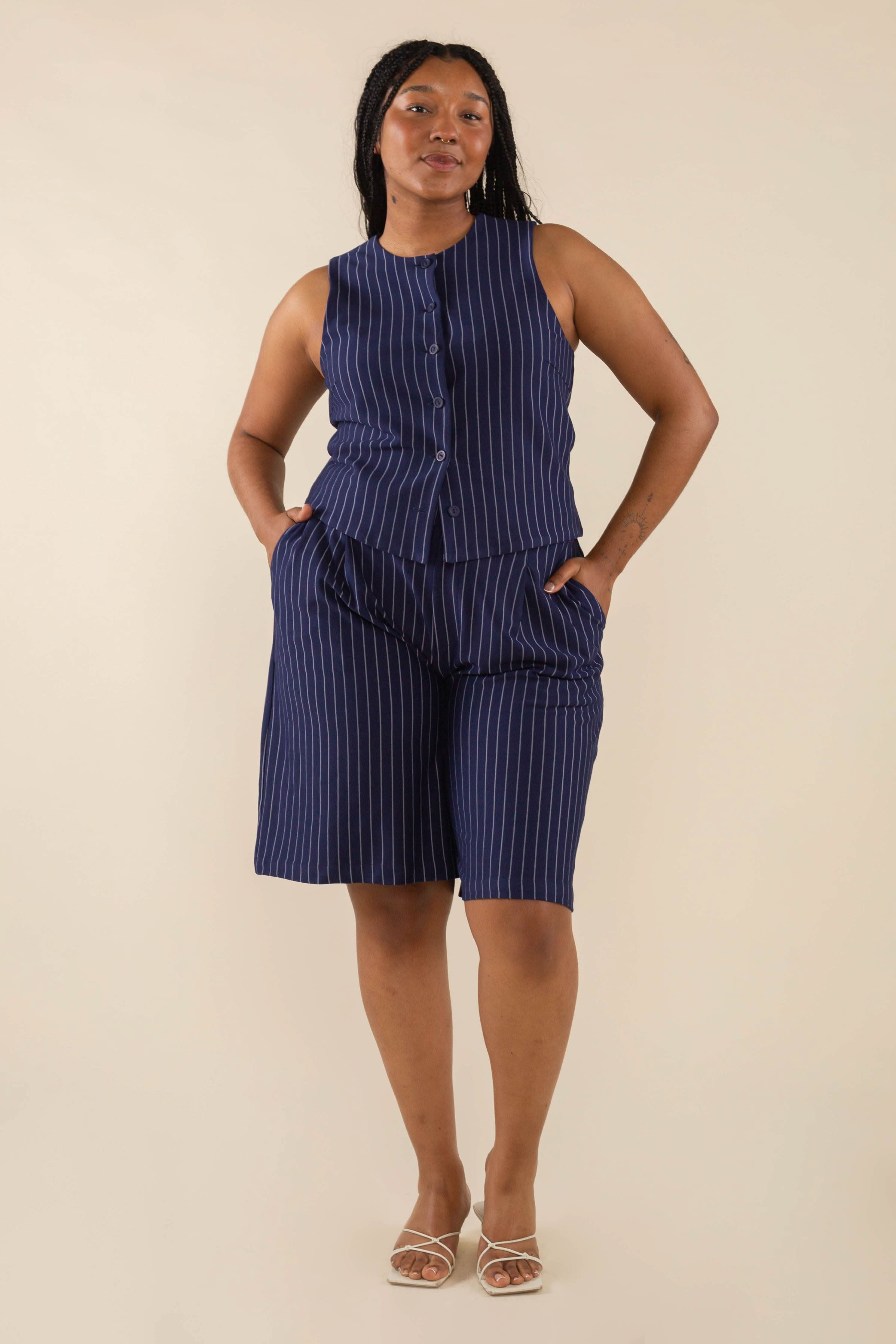 Woman wearing navy blue high neck vest with cream pinstripes. Vest has navy blue buttons all the way down