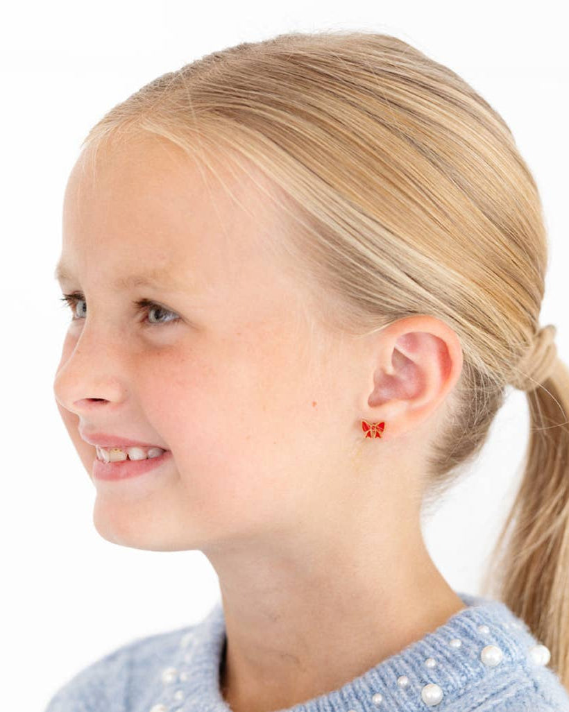 Young girl with blonde hair in a ponytail wearing butterfly-shaped earrings