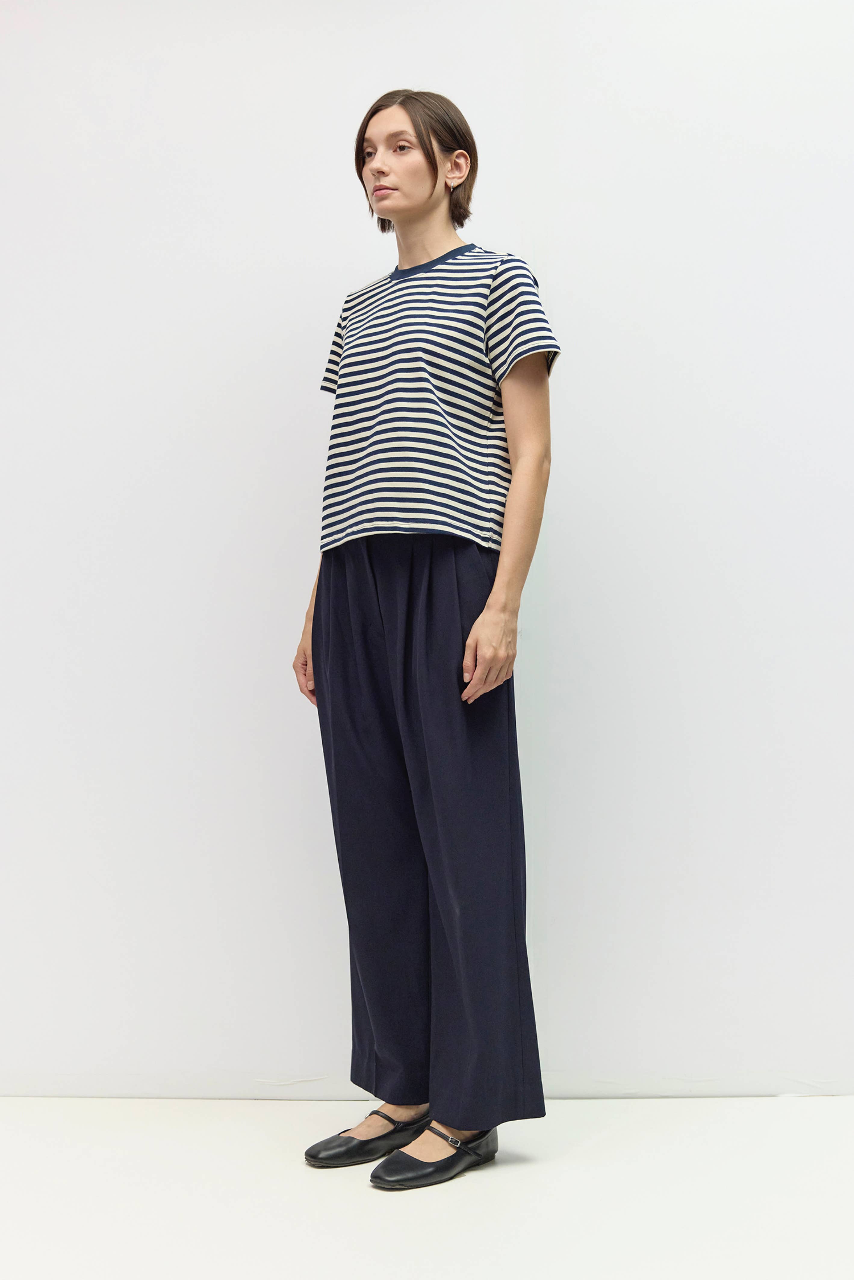 Woman wearing a striped shirt and wide-leg pants on a white background
