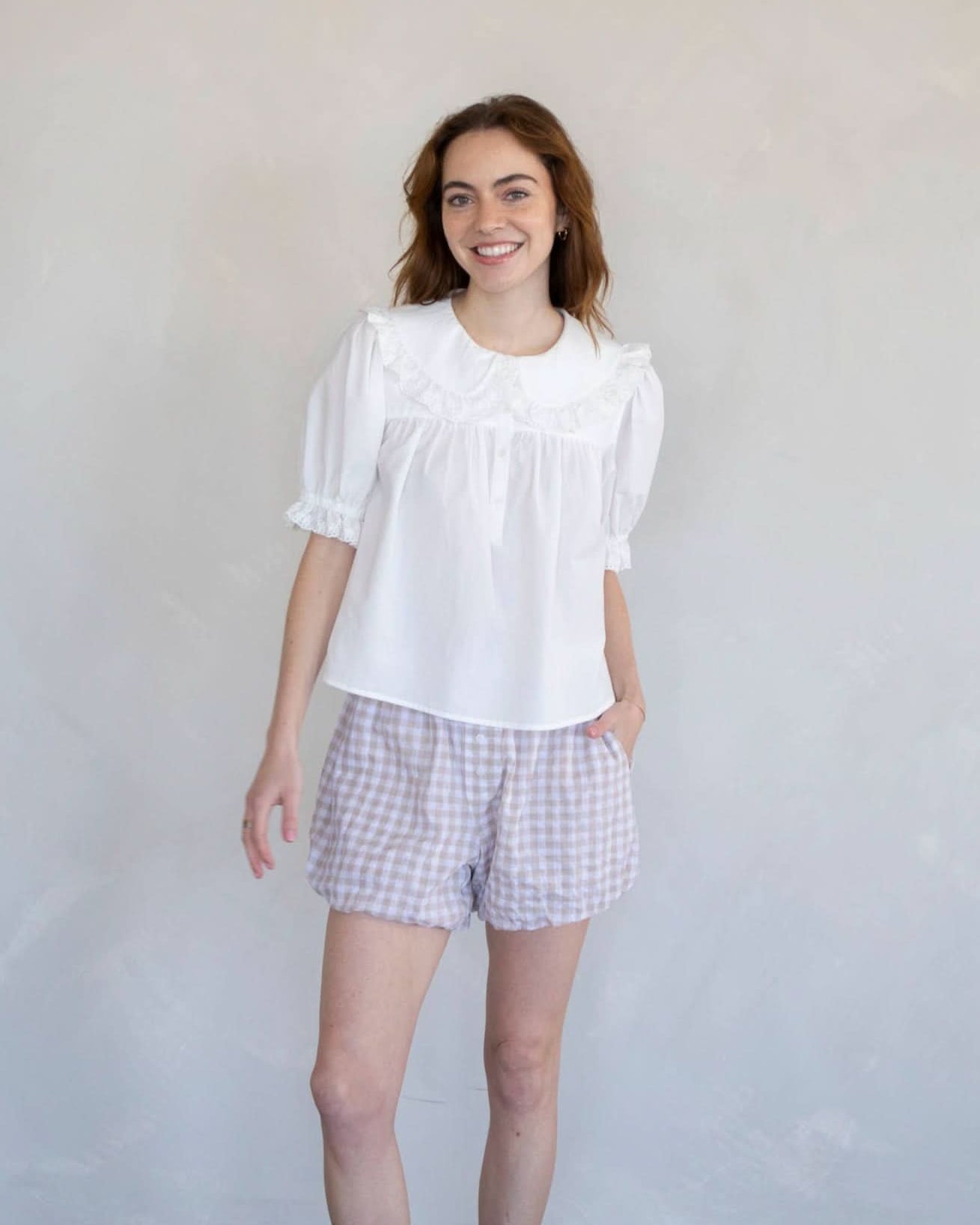 Woman wearing white half button dreamy sweetheart blouse and plaid shorts