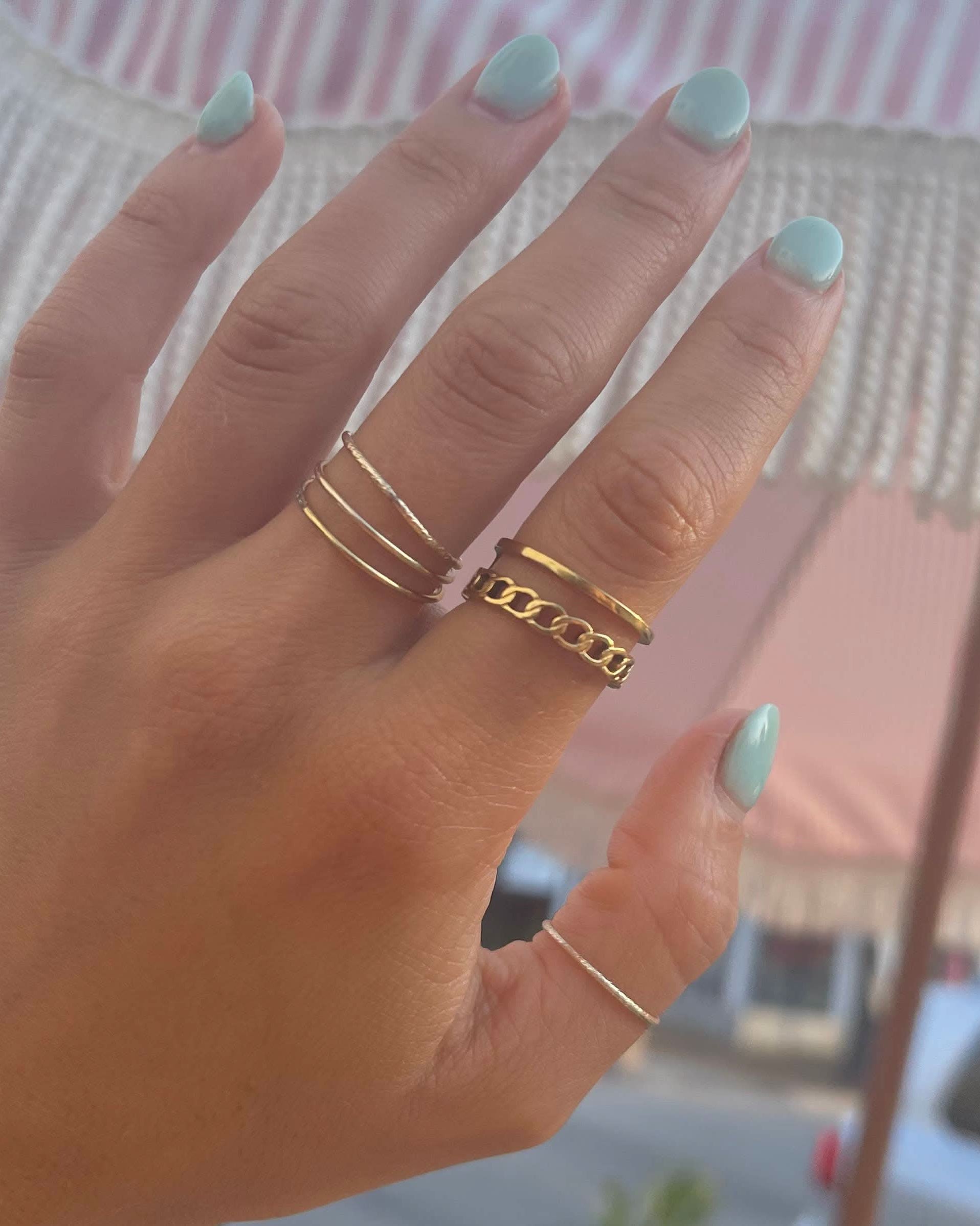 Woman wearing Simple thin gold ring in a stack with other gold rings