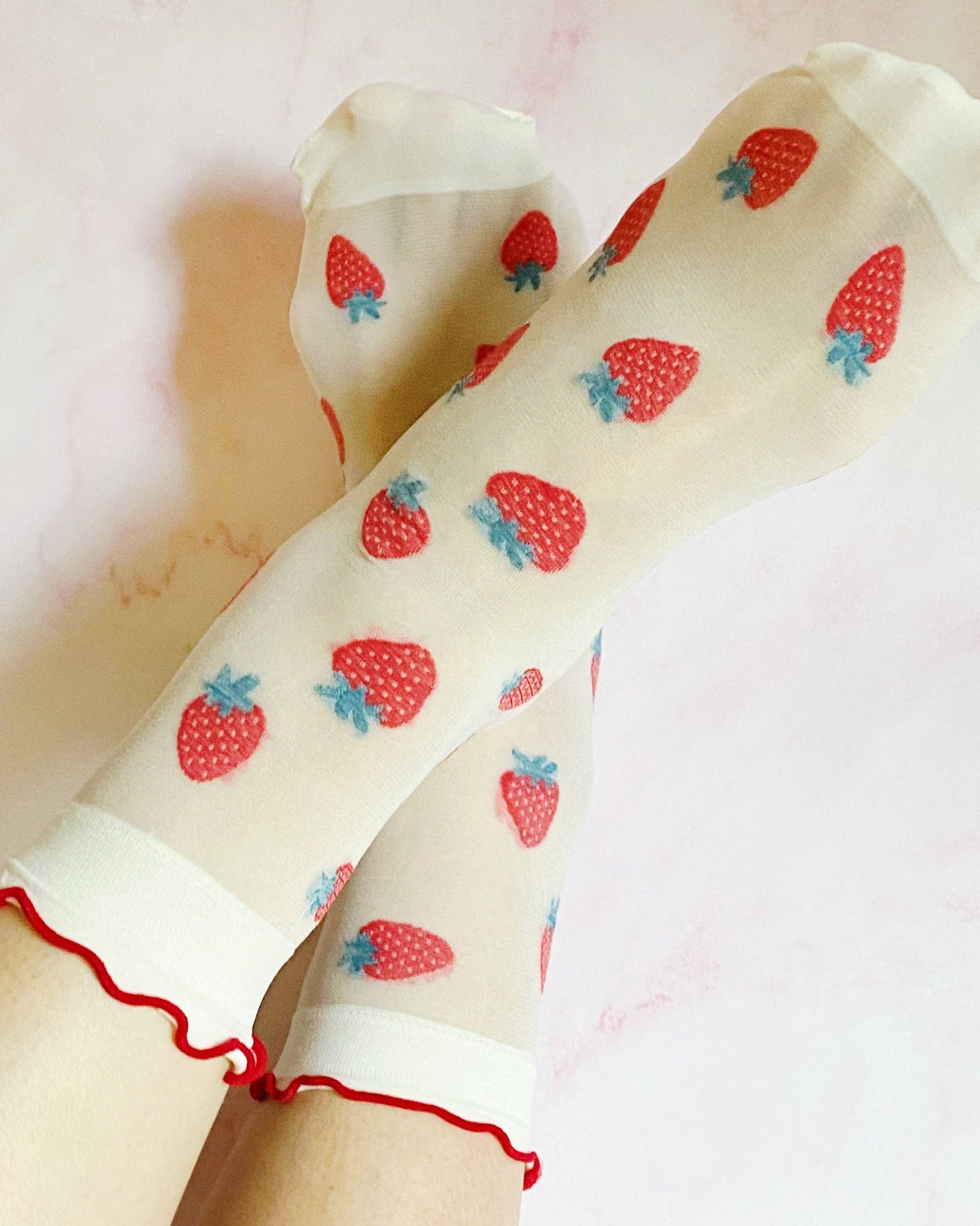 Sheer socks with strawberry pattern worn by a person on a light pink background