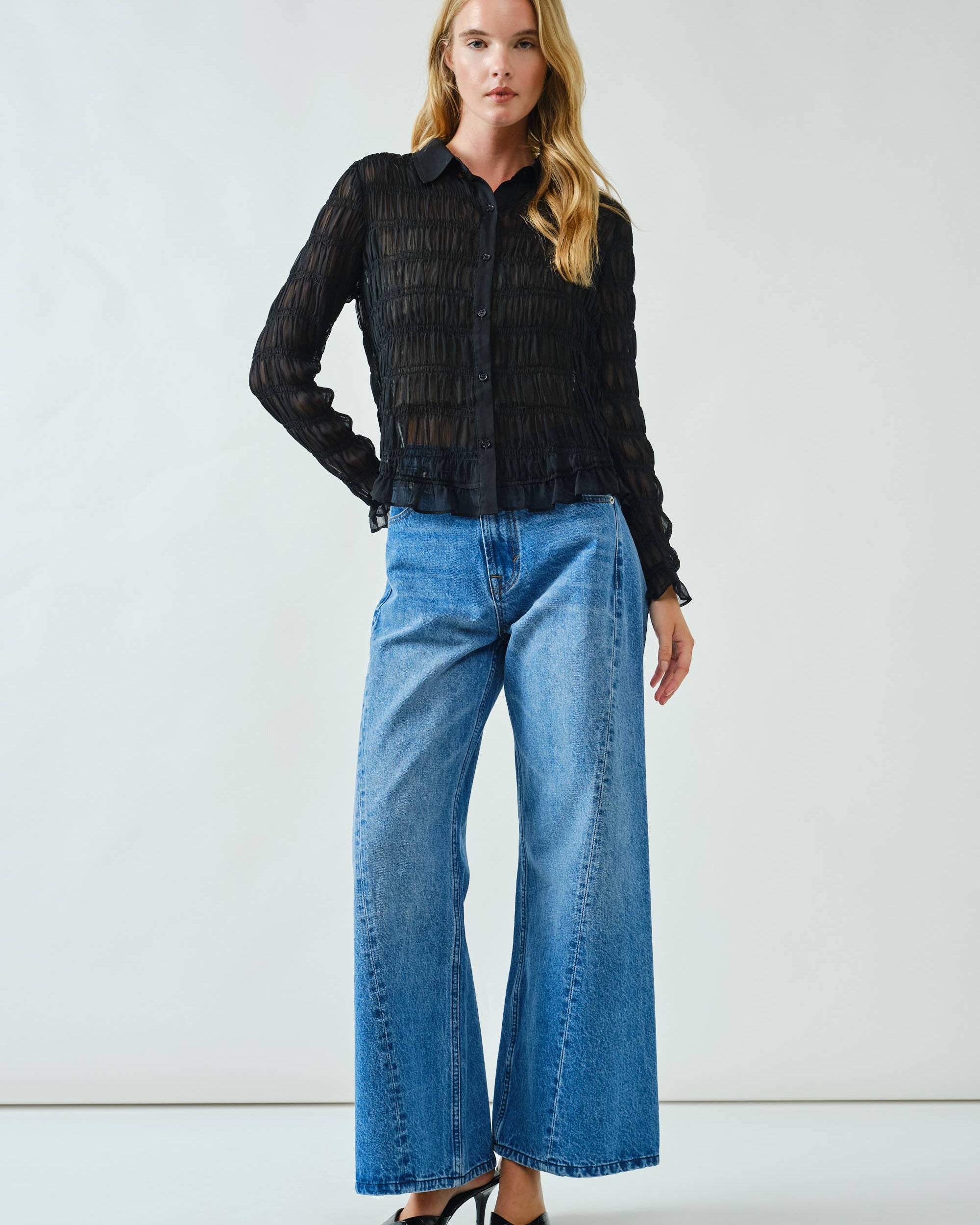 Woman wearing a black shirt and blue jeans against a white background