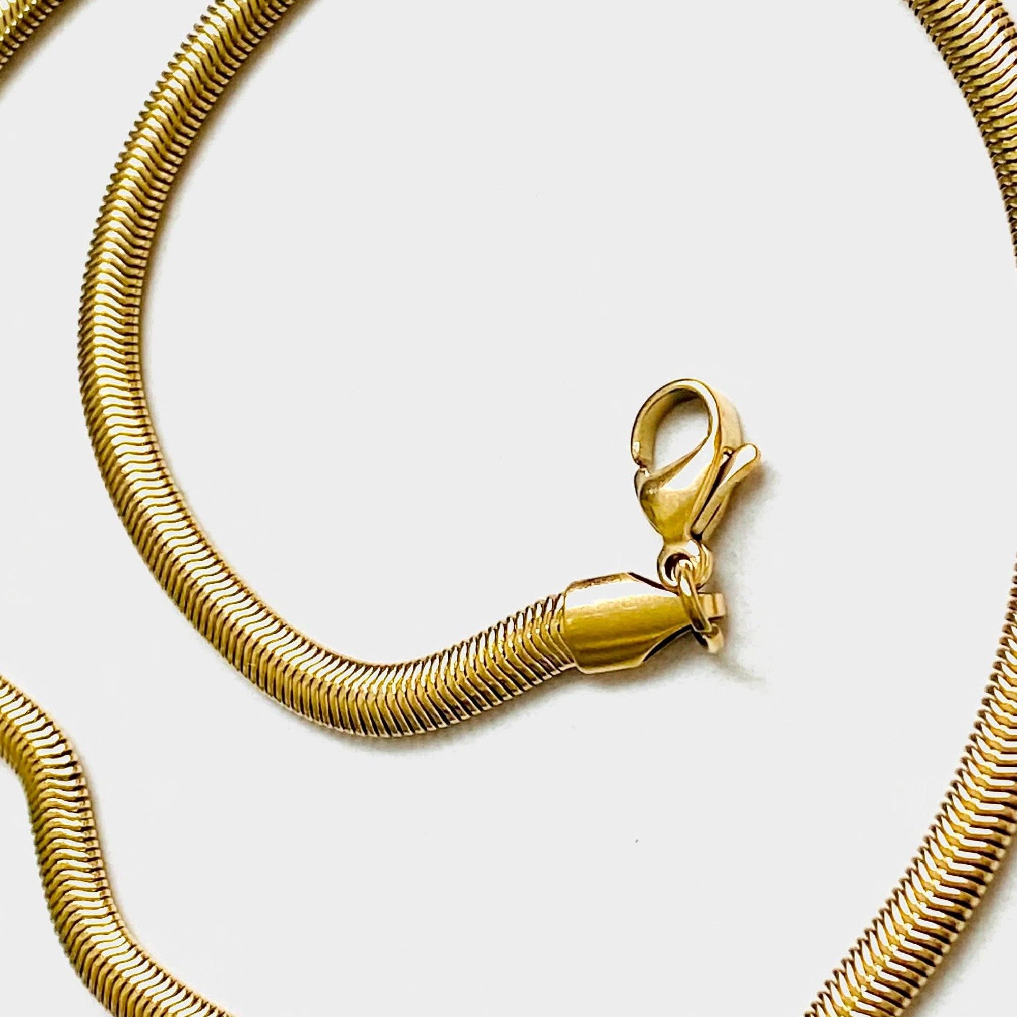 Close up on lobster clasp of 18k gold 15 inch to 17 inch herringbone necklace laid out in a swirl pattern on white background